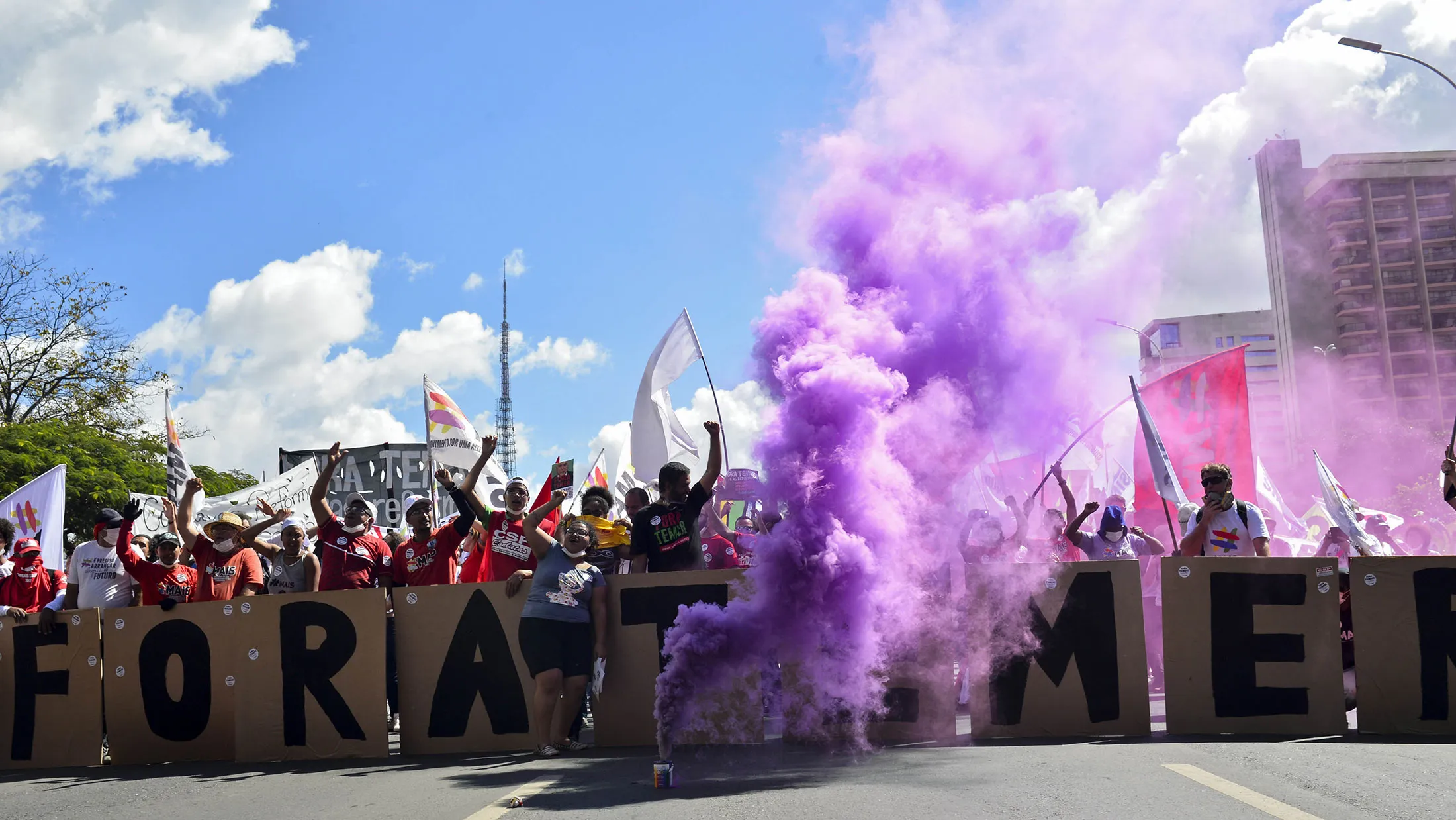 Smoke rises as demonstrators hold placards and flags during protests outside of the National Congress demanding the resignation of Brazilian President Michel Temer in Brasilia on May 24, 2017.
