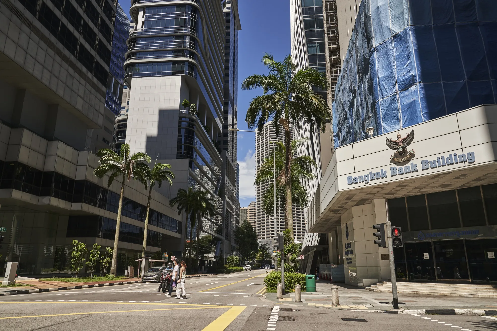 Pedestrians cross a street outside the Bangkok Bank building&nbsp;in the central business district of Singapore.
