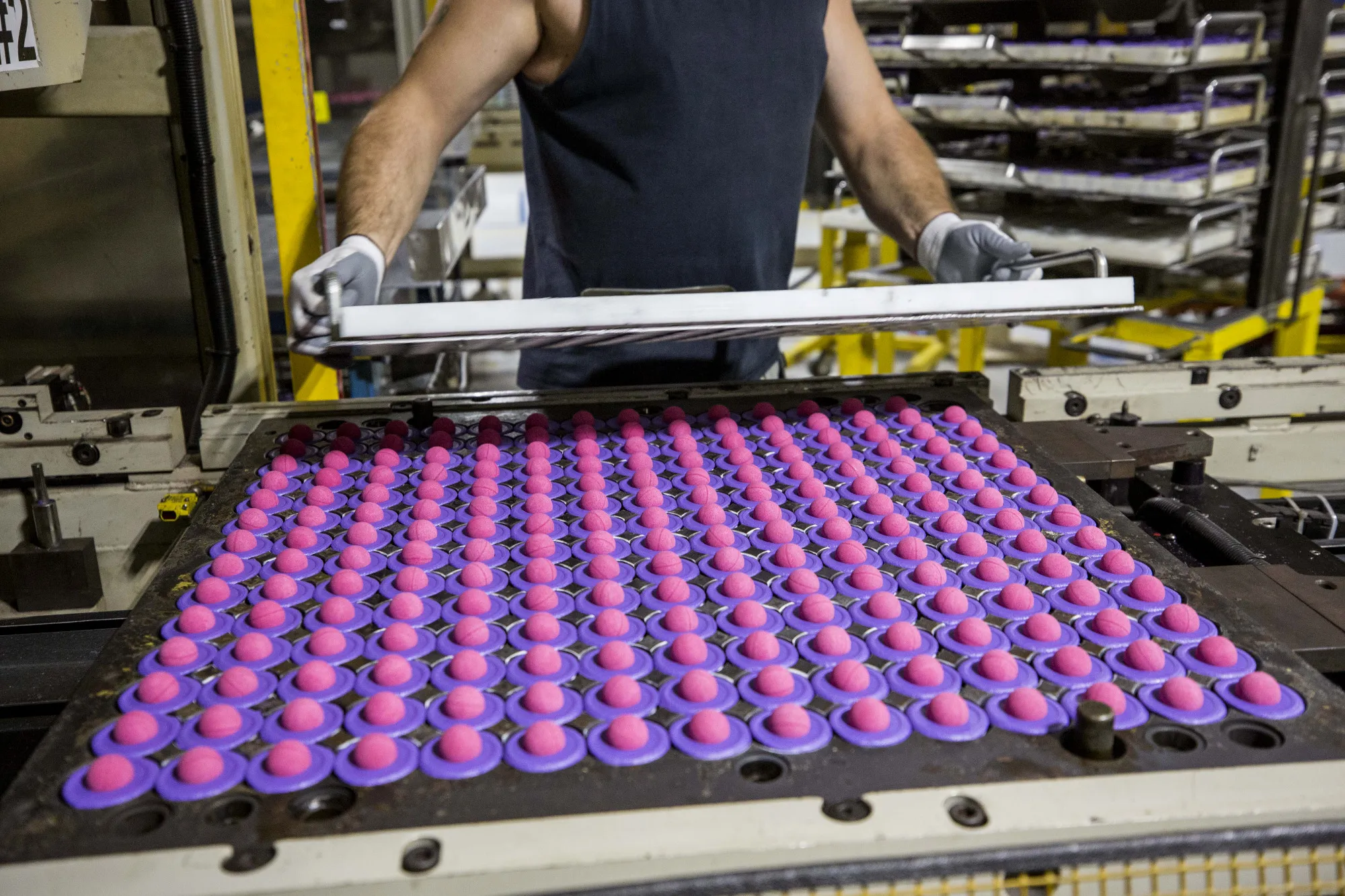 A worker removes the lid on a tray of finished pink rubber golfball cores at the Acushnet Holdings Corp. Titleist Ball Plant III facility in New Bedford, Massachusetts, U.S., on Friday, Oct. 20, 2017. The U.S. Census Bureau is scheduled to release durable goods figures on October 25.