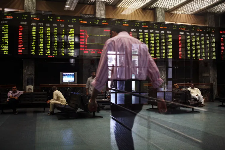 Traders are seen through reflected glass in the the Karachi Stock Exchange in Karachi, Pakistan.