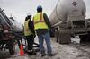 Employees look on as liquid propane is transloaded from a truck to a rail car in North Dakota.
