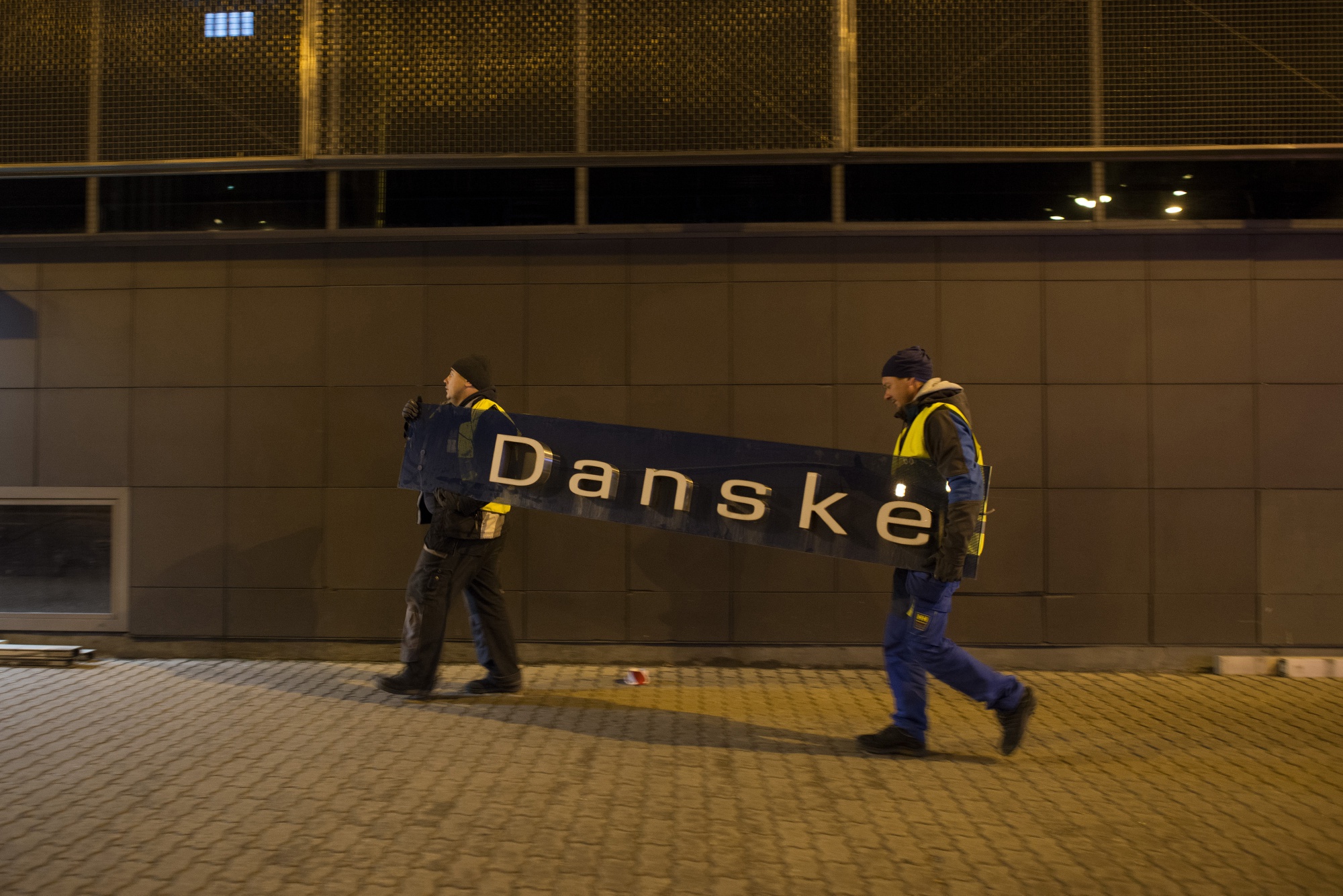 Workers remove Danske signage and carry it to a trailer at the former Danske Bank A/S branch in Tallinn, Estonia, on Oct. 5.