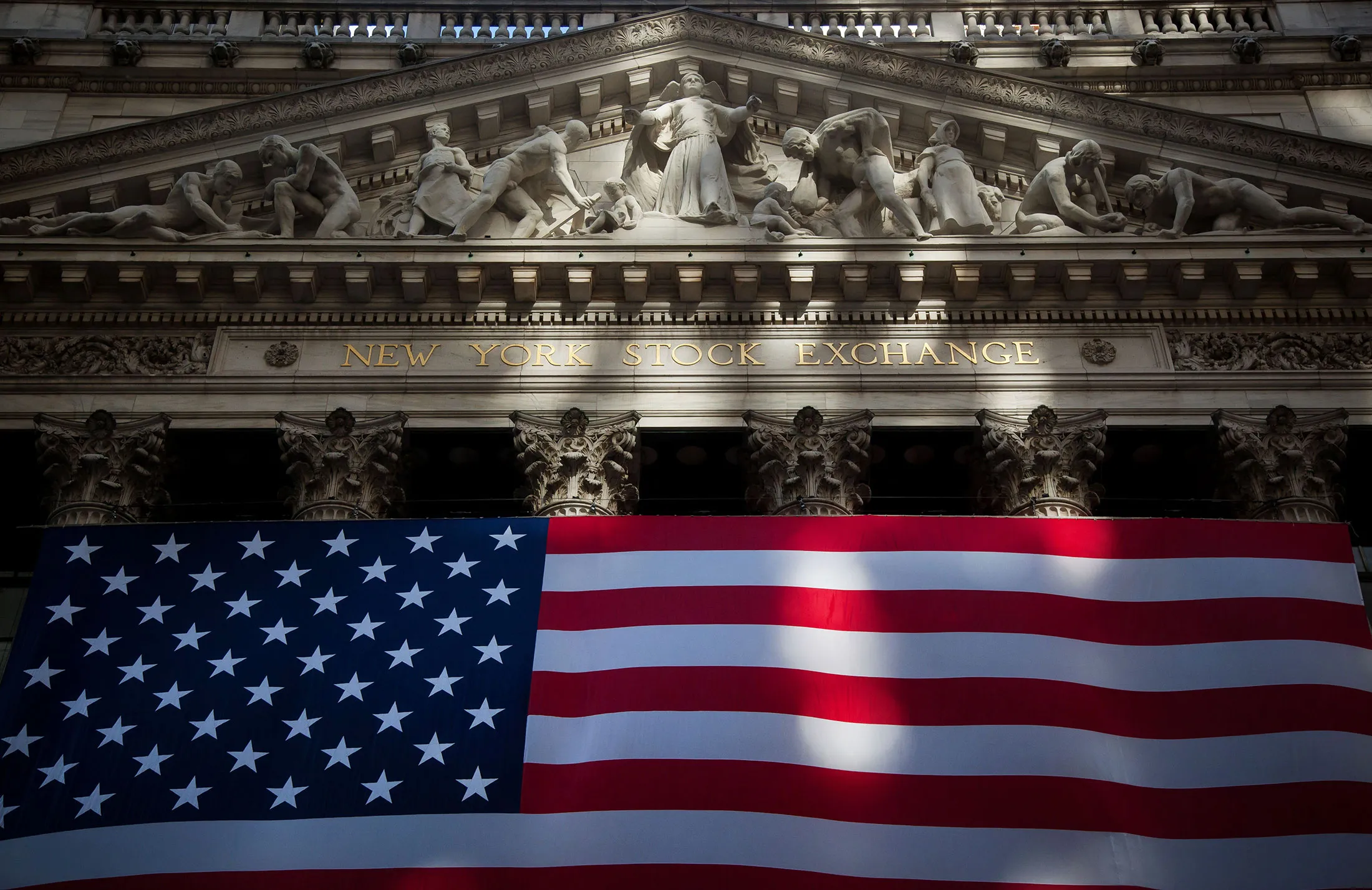 An American flag is displayed at the New York Stock Exchange on Friday, Nov. 11, 2016. U.S. stocks fluctuated in whipsaw trading, with the Dow Jones Industrial Average spinning near a record, as investors guess how Donald Trump's policies will affect the economy and interest rates. Small caps appear headed for the best weekly gain in five years.
