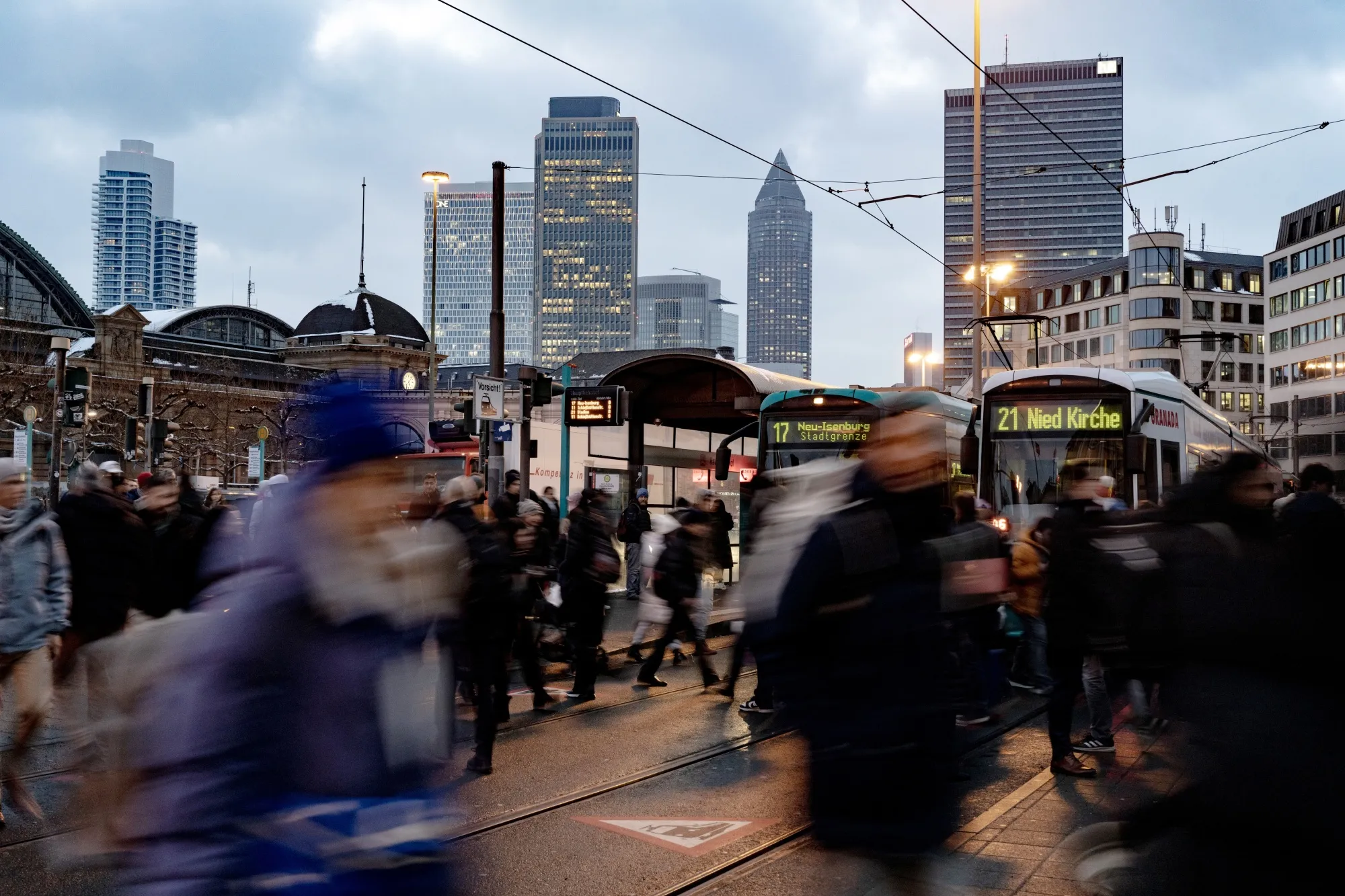 Commuters cross a road outside Frankfurt Central Station in Frankfurt, Germany.