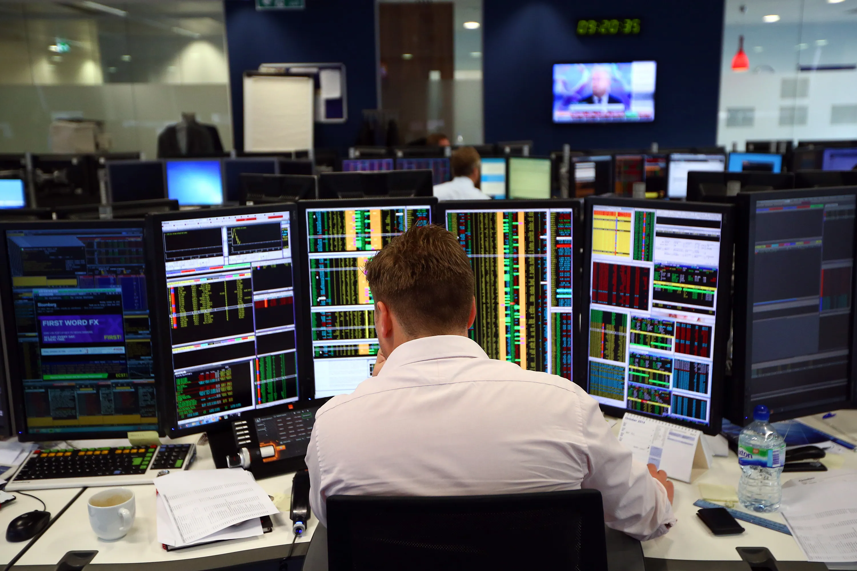 An investment trader looks over trading screens.