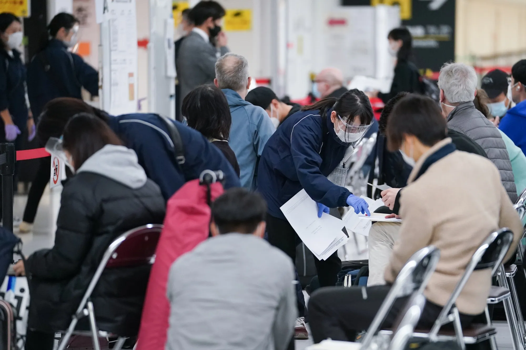 A worker wearing a protective mask assists travelers arriving at Narita airport near Tokyo in November.&nbsp;