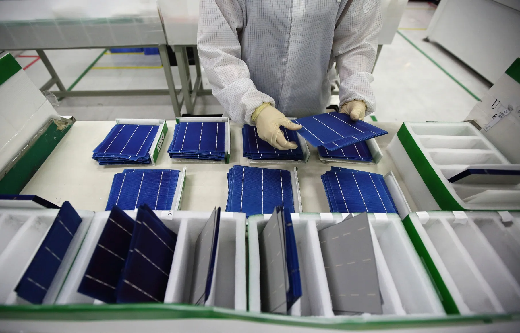 An employee performs a final inspection on solar cells on the production line at the Trina Solar factory in Changzhou, Jiangsu Province, China.