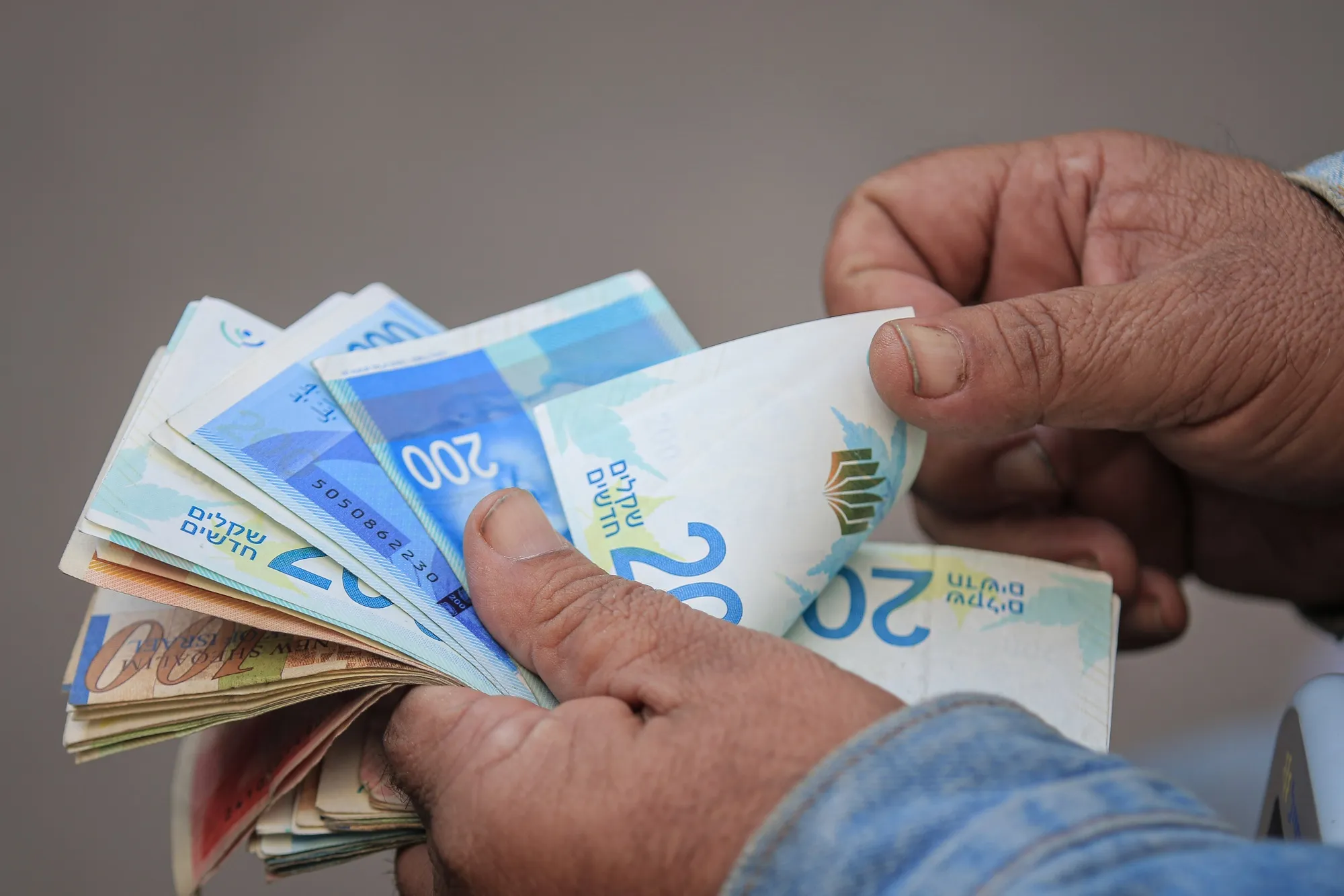 A man counts Israeli shekel banknotes