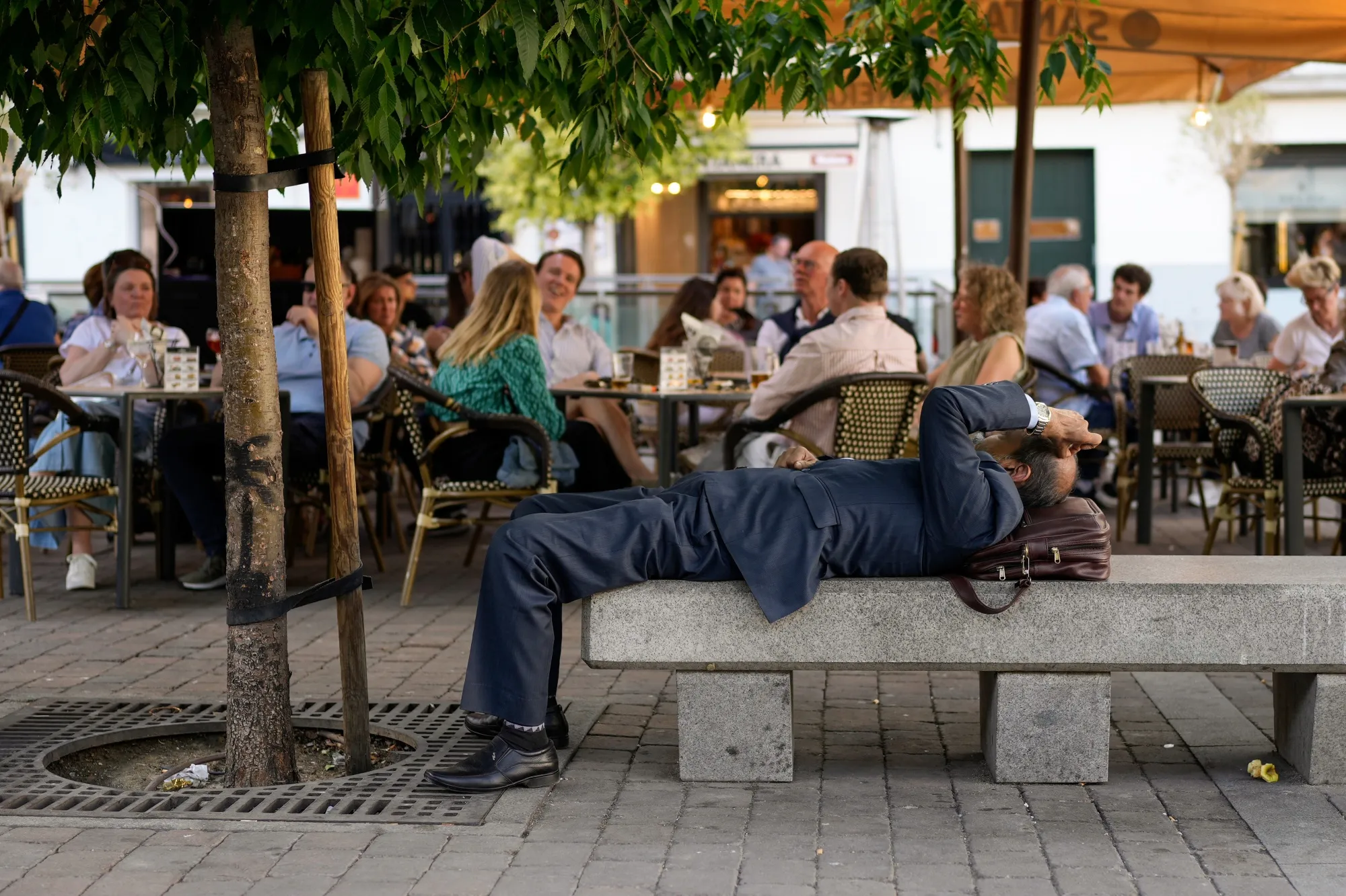 An office worker rests in the shade in front of a cafe terrace area during high temperatures in Madrid, Spain, on Thursday, April 27, 2023.&nbsp;