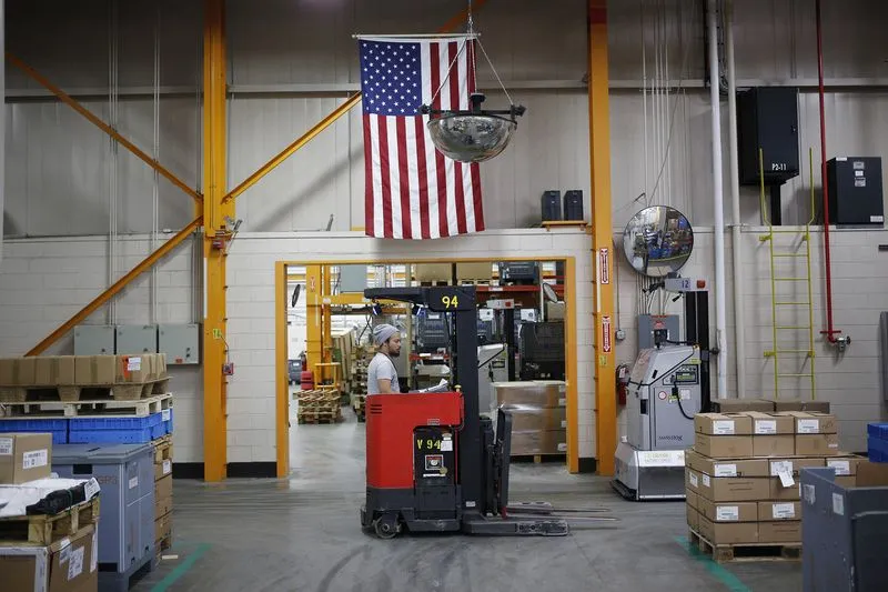 An American flag hangs above a worker operating a forklift at a manufacturing facility in Virginia Beach, Virginia.