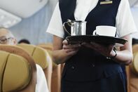 Flight attendant holding tray with coffee, mid section
