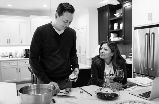 Murvartian works on a laptop computer as her husband prepares dinner next to her in the kitchen.