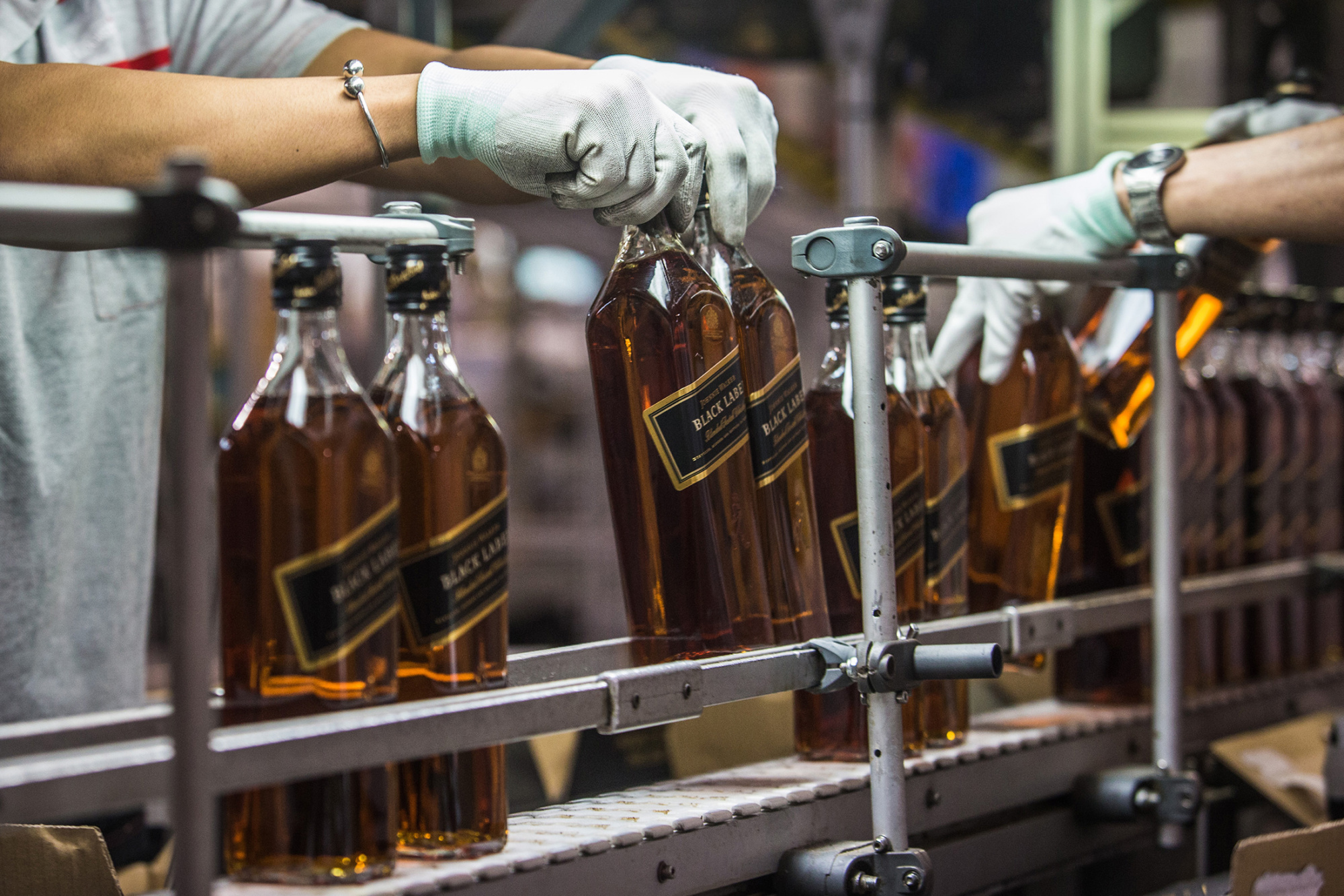 Employees box bottles of Johnnie Walker Black Label Scotch on the postponement line at the Diageo Plc International Supply Center and Technical Centre in Singapore, on Wednesday, Aug. 26, 2015.
