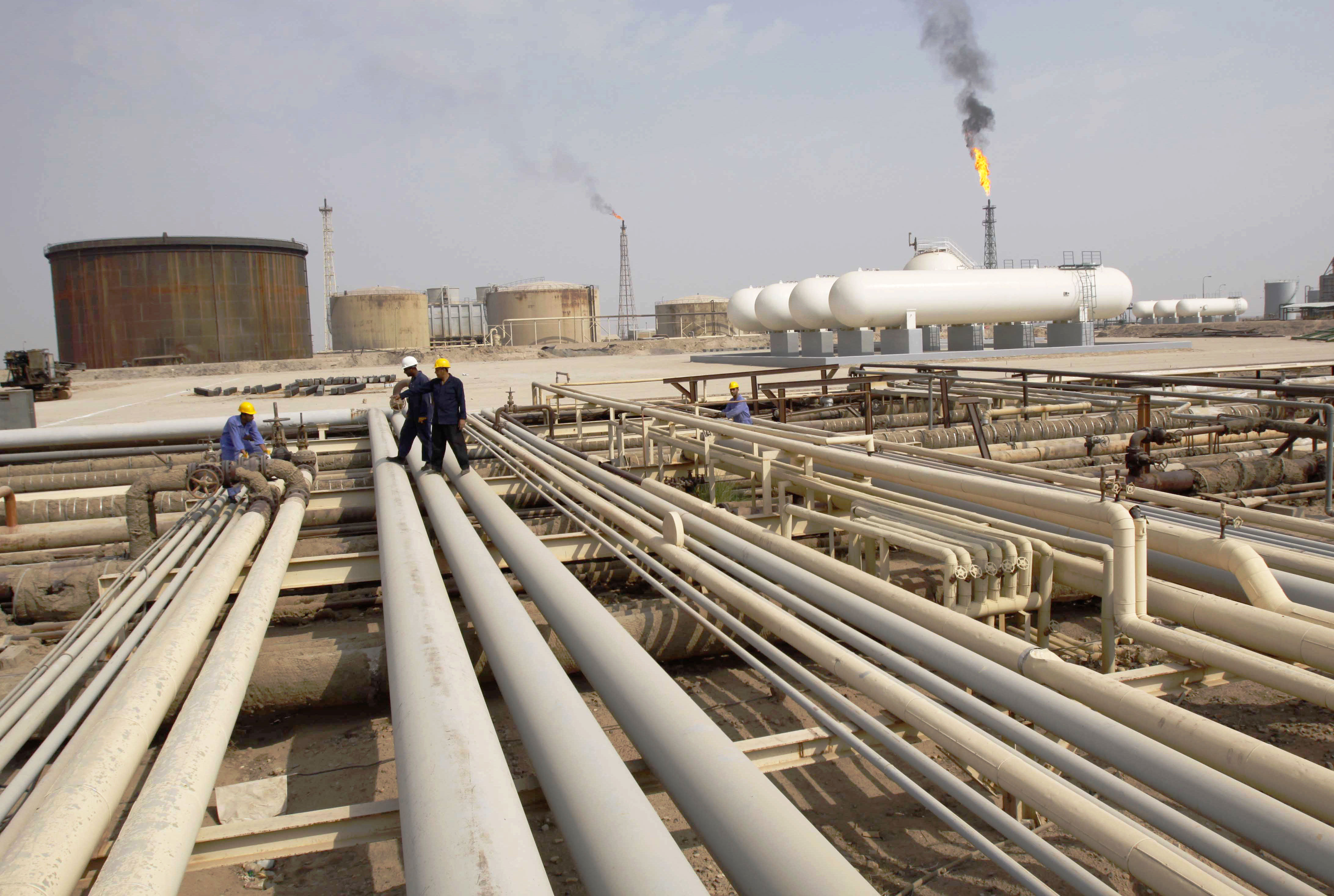 Iraqi workers walk on pipelines of an oil refinery near the city of Basra in 2009. In November of that year, Iraq awarded&nbsp;the right to develop the West Qurna-1 field to a consortium led by Exxon and Shell.