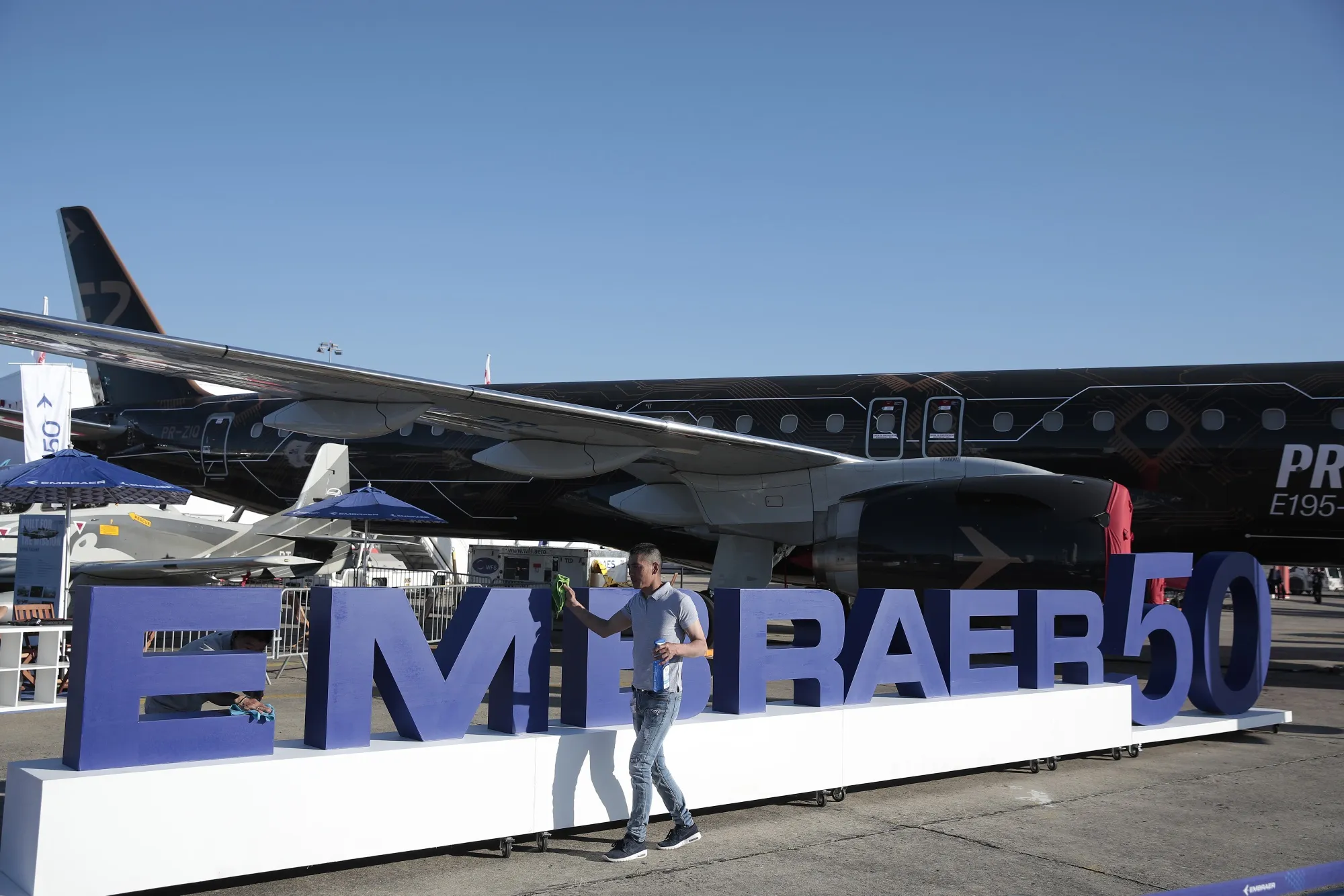 An employee cleans a logo celebrating the 50th anniversary of Embraer SA near an E195-E2 series jet&nbsp;during the 53rd International Paris Air Show, in June 2019.