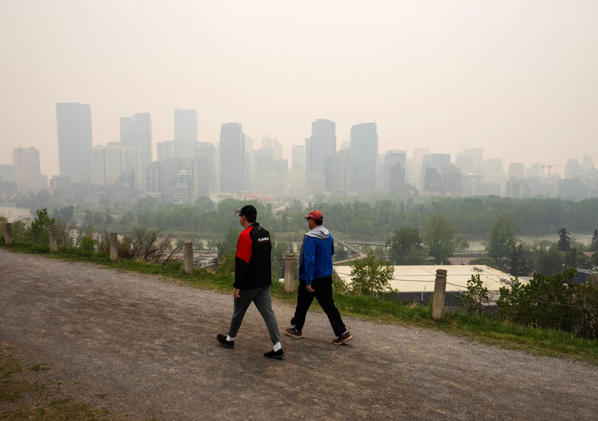 Pedestrians pass buildings shrouded in smoke from wildfires in Calgary, Alberta.