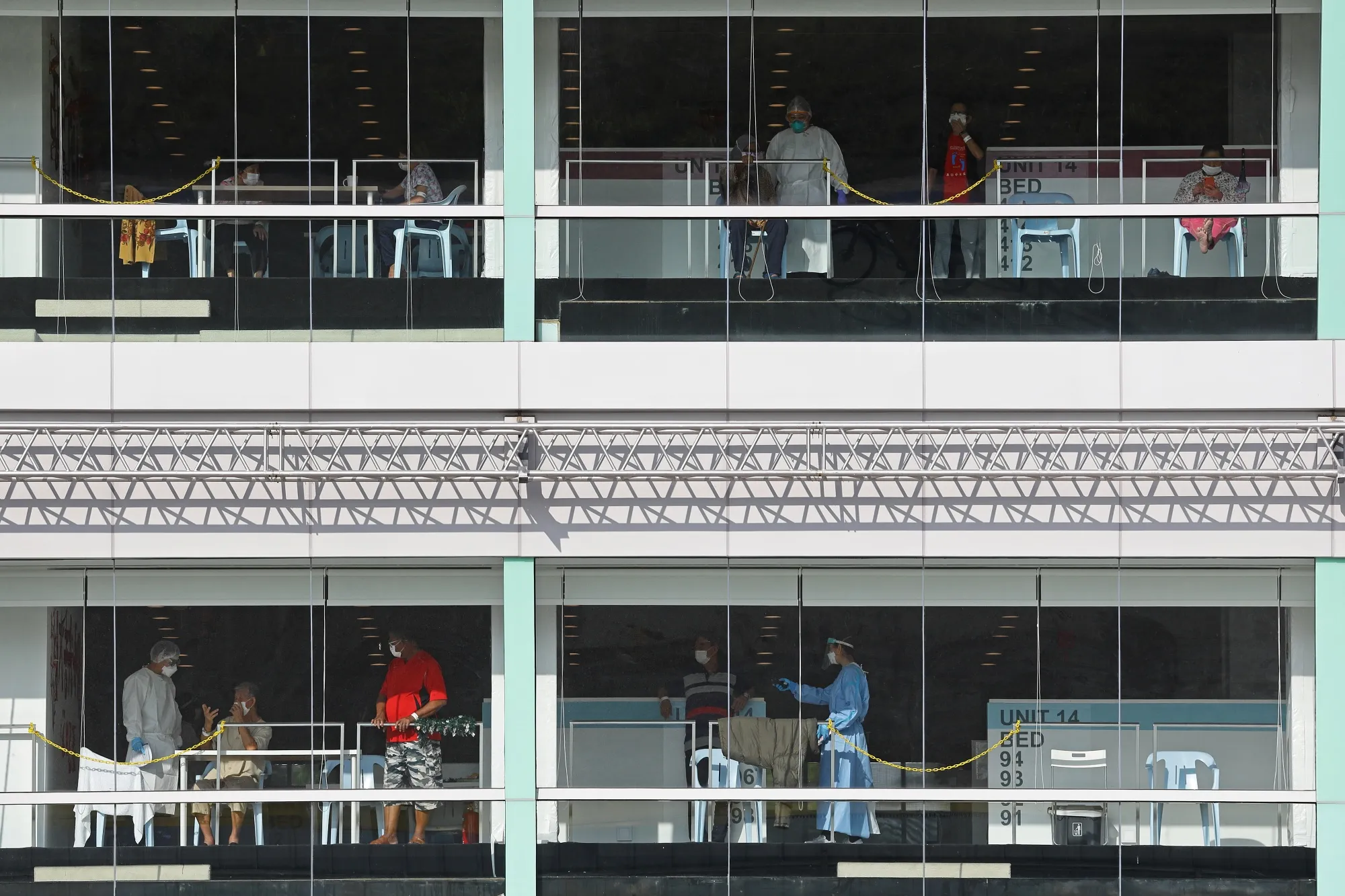Healthcare workers in PPE with Covid-19 patients at the Formula One Pit building, which was converted into a treatment facility, in Singapore on Feb 19. 