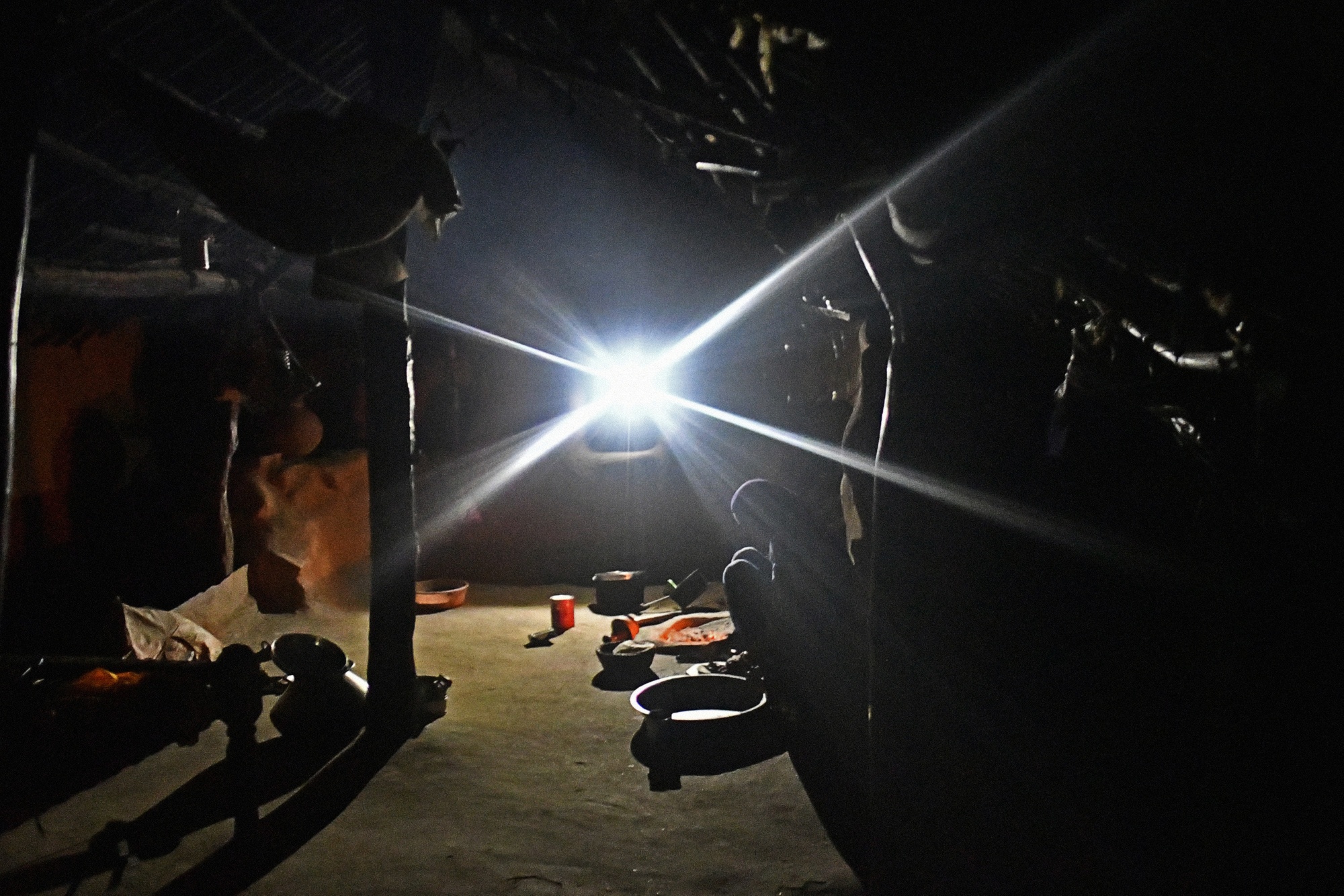 A woman prepares food inside a home illuminated by a single light-emitting diode (LED) lamp in Kraska village, Rajasthan, India, on Monday, April 16, 2018.