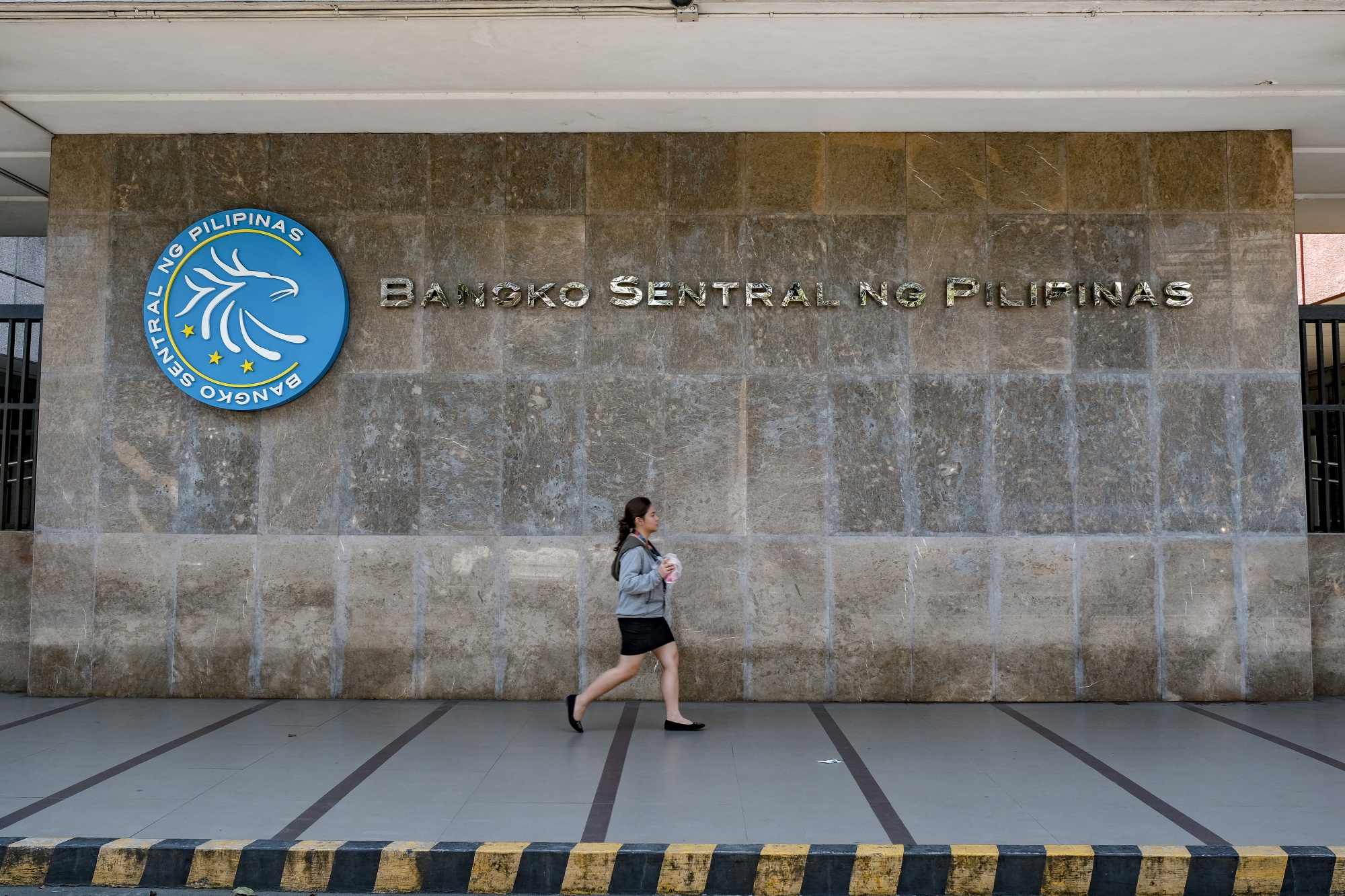 A woman walks past signage displayed at the Bangko Sentral ng Pilipinas headquarters in Manila.