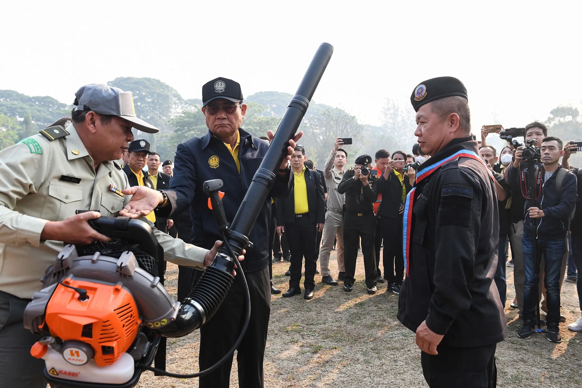 Prayut Chan-O-Cha, center, hands a leaf blower to an official at an army base in Chiang Mai on April 2.