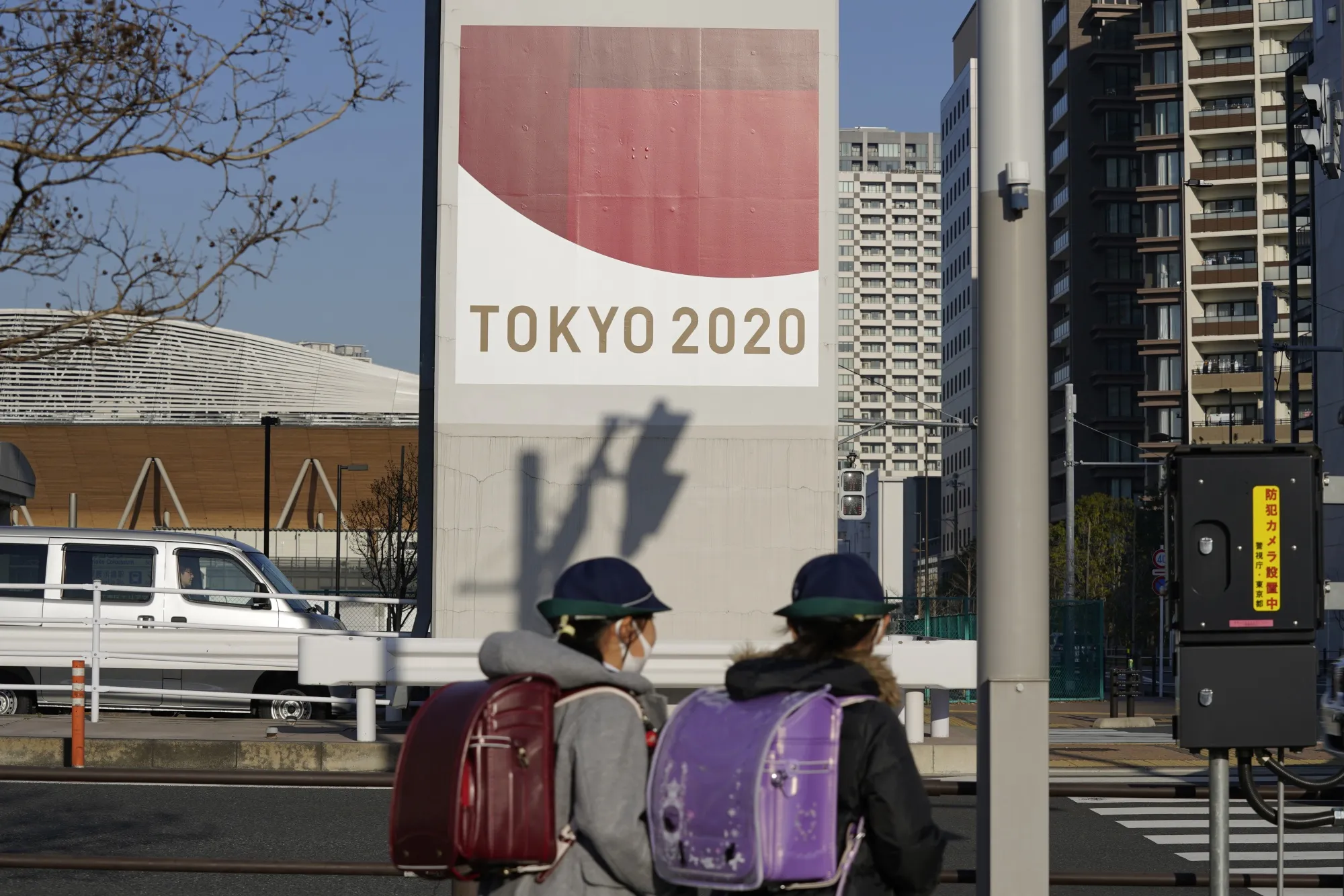 Students walk past an advertisement for the now-postponed Tokyo 2020 Olympic Games in front of Ariake Gymnastics Centre, the venue for gymnastics events at the Olympics, in Tokyo.