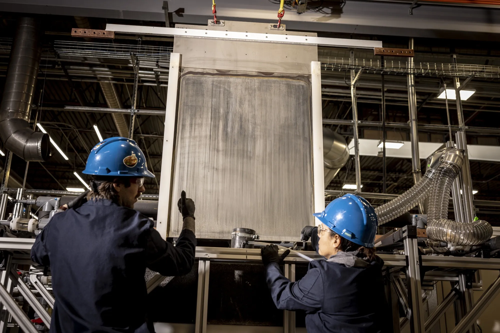 Employees guide a cathode coated with 99% pure iron out of an electrowinning cell at the Electra production facility in Gunbarrel, Colorado.&nbsp;