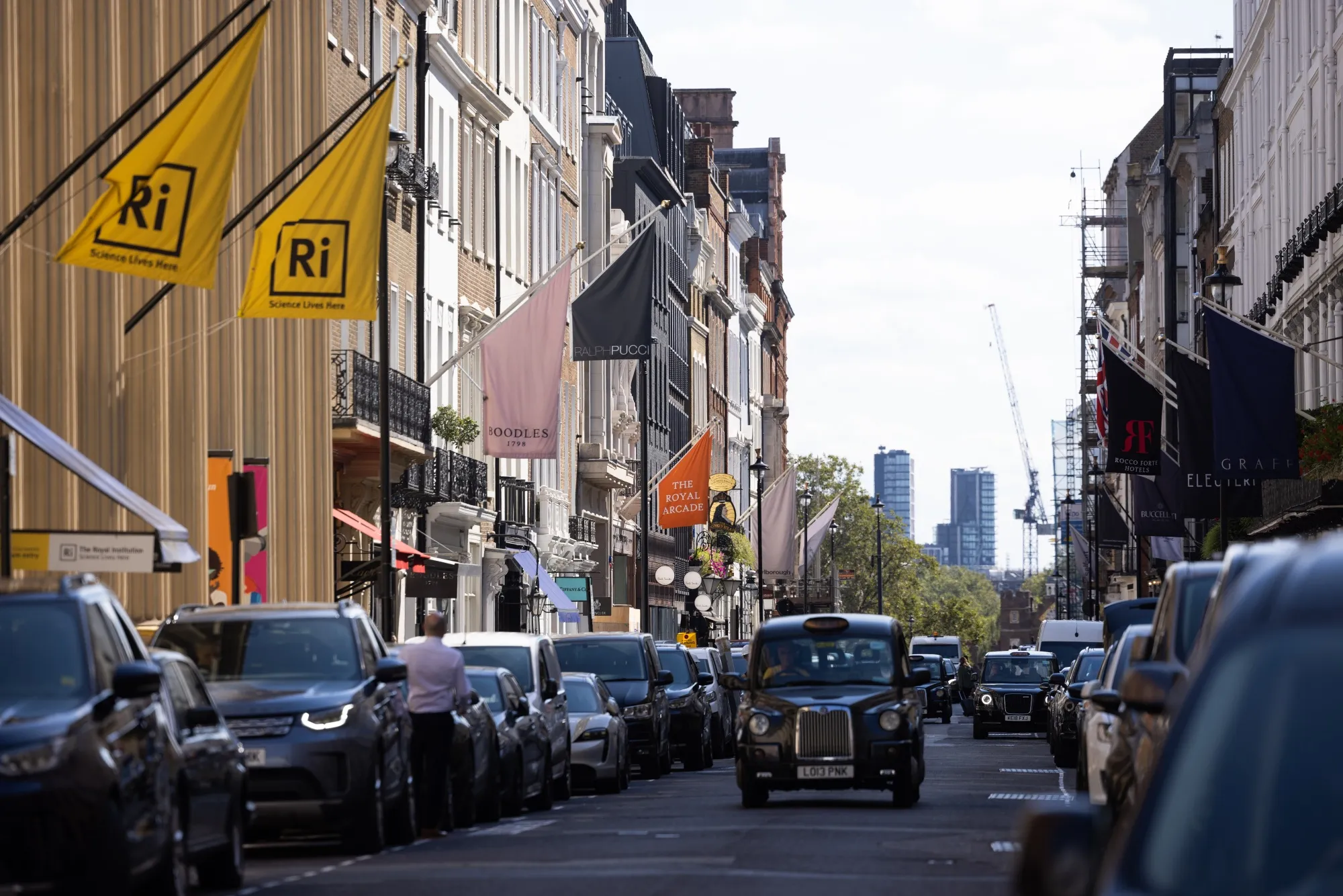 Black taxi&nbsp;cabs pass shops and restaurants in London’s&nbsp;Mayfair neighborhood.&nbsp;