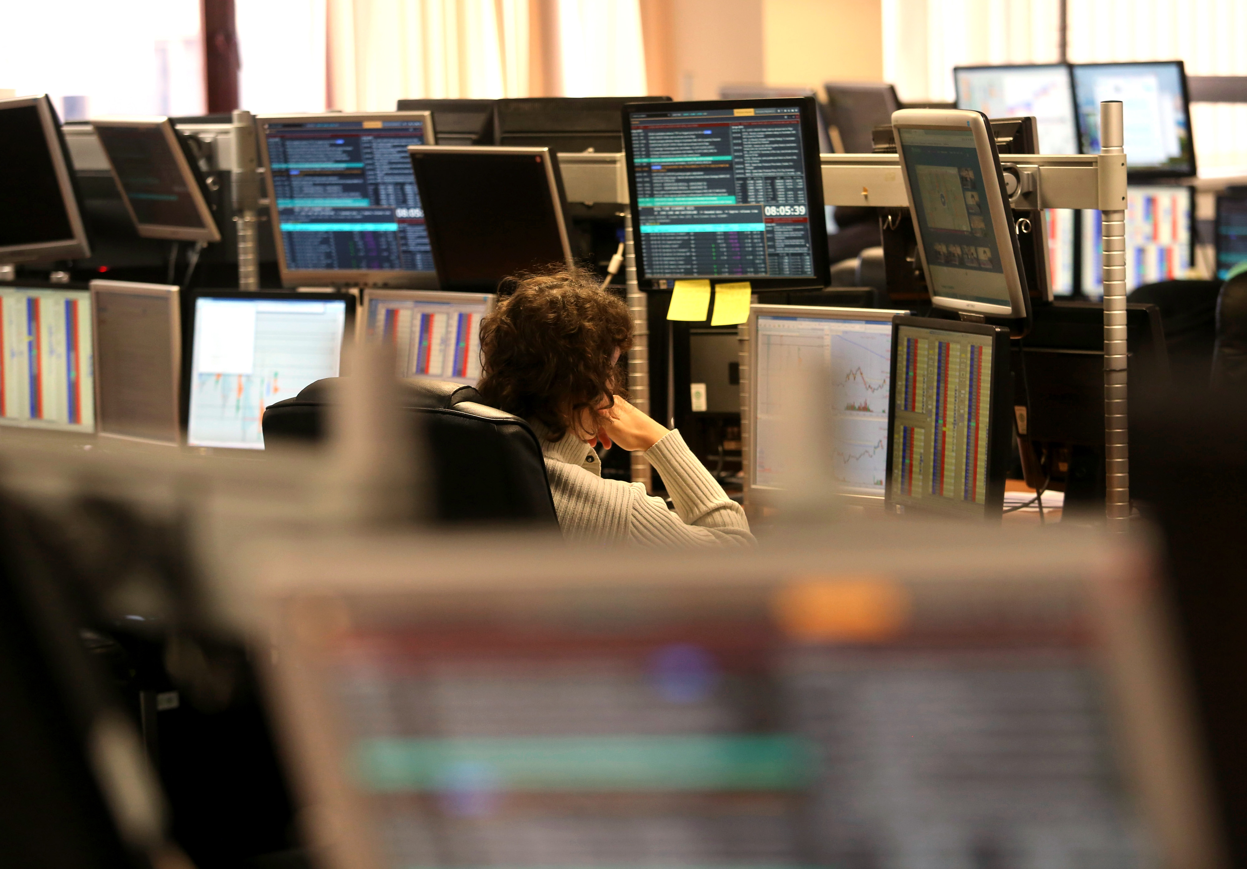 A trader sits and monitors his computer screens.
