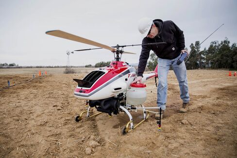 A drone operator checks over a Yamaha crop duster before a test flight at a UC Davis testing area.