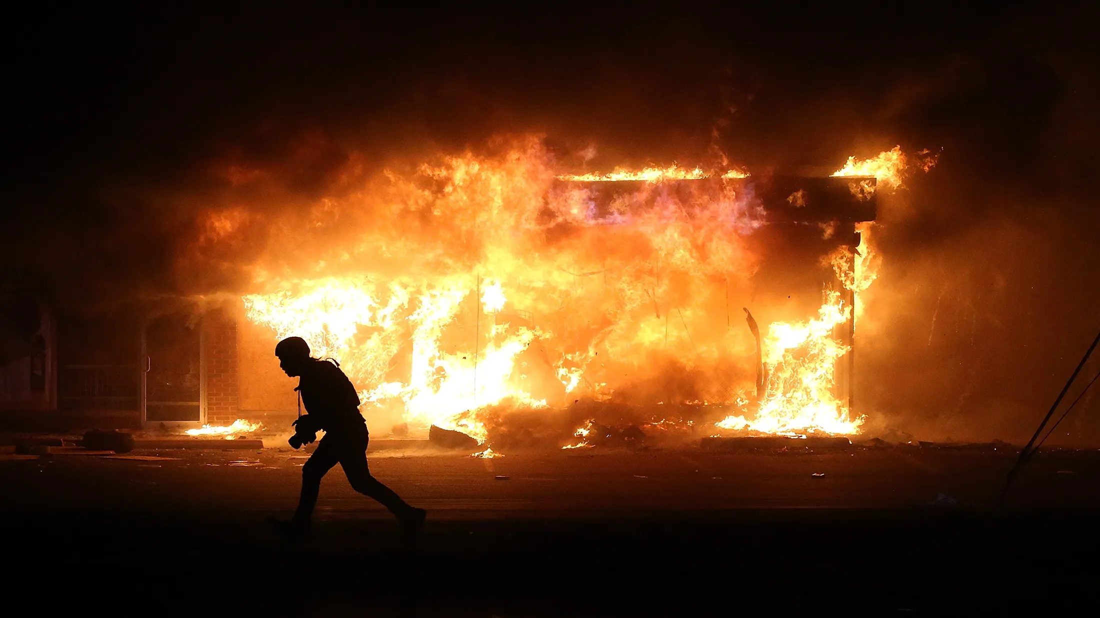 A photographer runs by a burning building during a demonstration in Ferguson, Missouri, on on Nov. 25, 2014.
