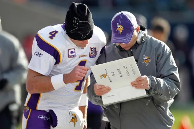 Minnesota Vikings quarterback Brett Favre checks out a book of Polaroid sideline photos with a coach during an NFL game against the Bears on Nov. 14, 2010 in Chicago