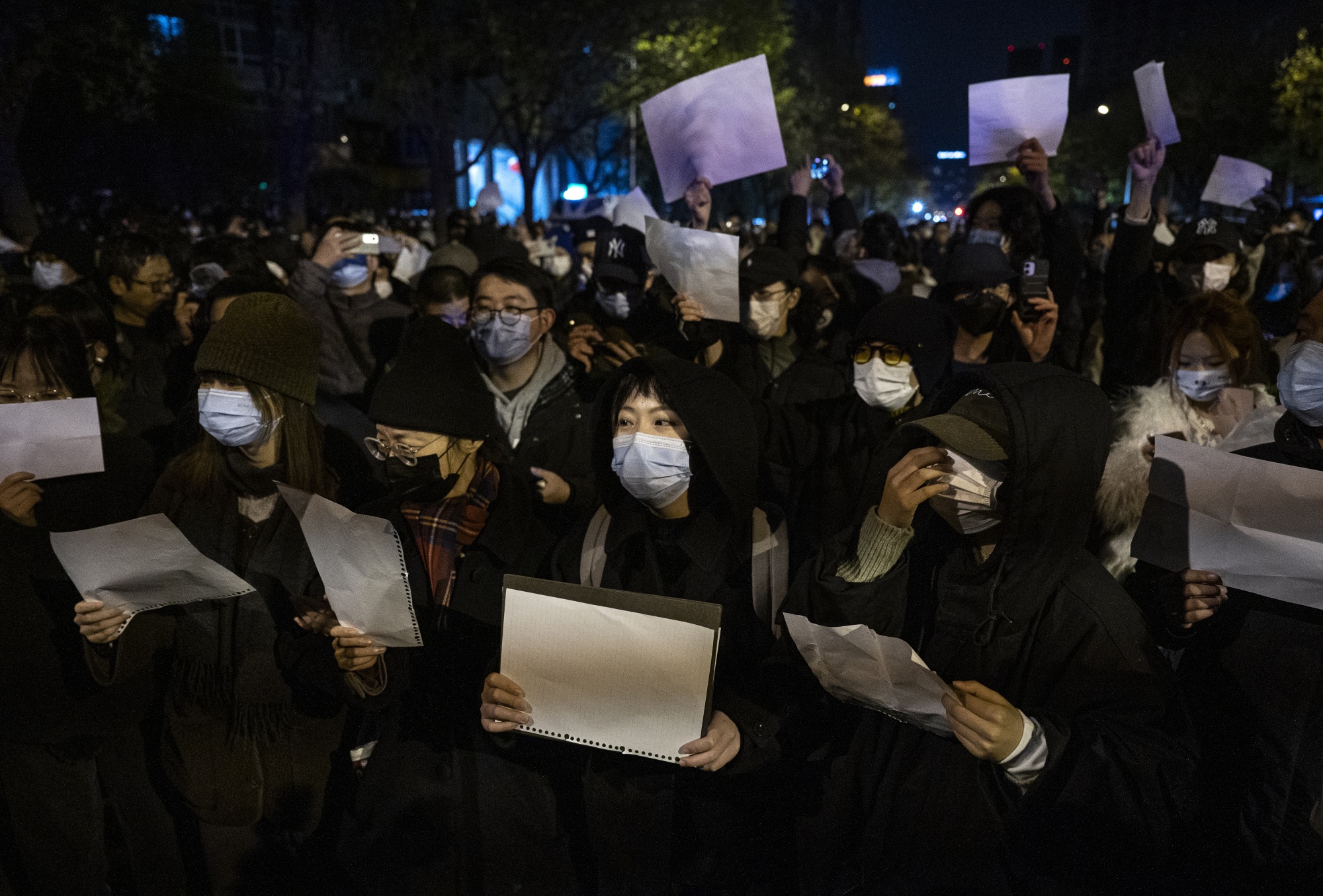 Protesters hold up blank pieces of paper during a protest in Beijing on Nov. 27.