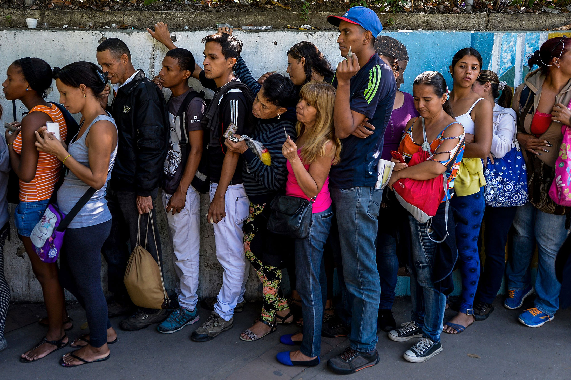 People queue to buy basic food and household items outside a supermarket in Caracas, on Sept. 28, 2016.
