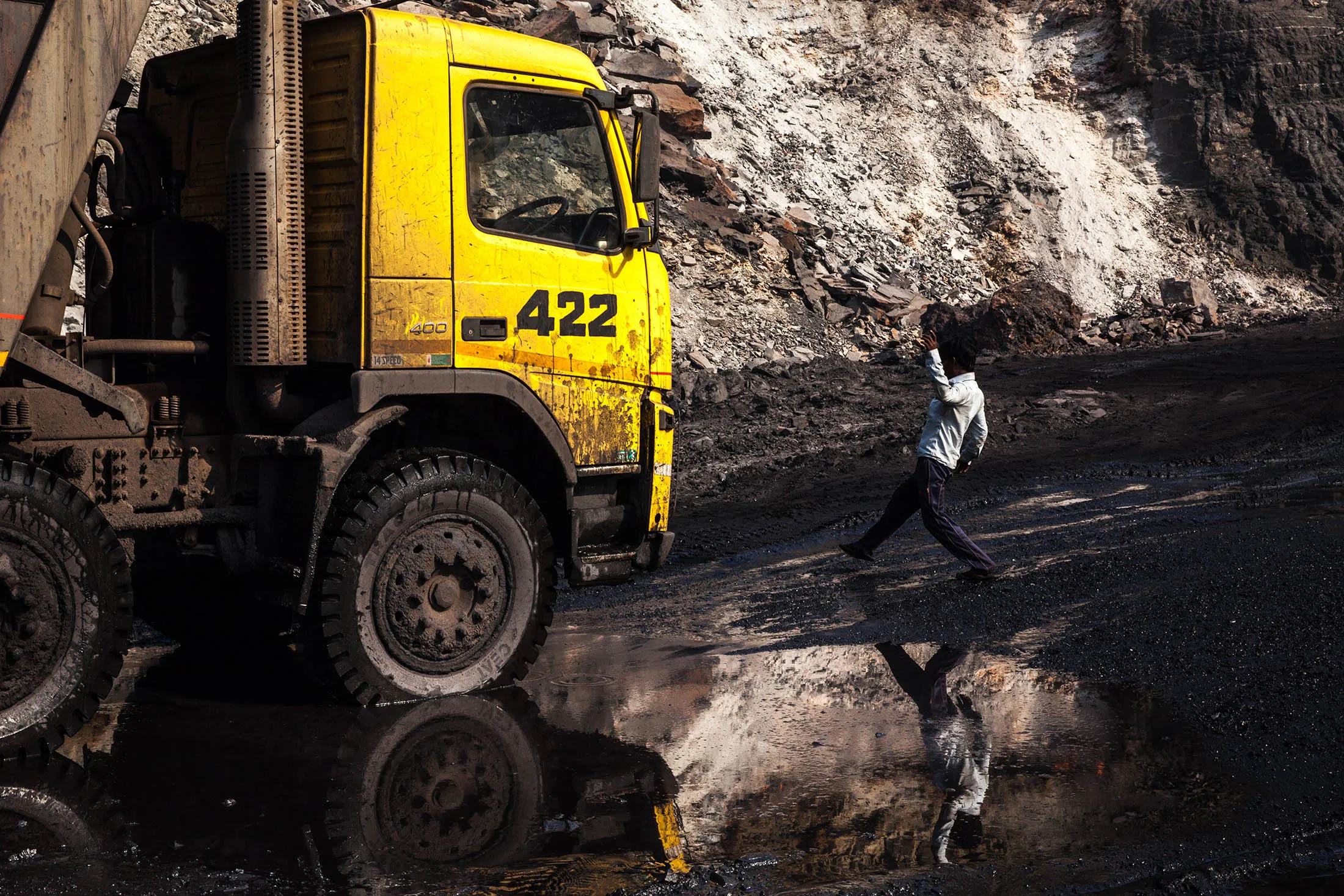 A worker is reflected in a puddle as he walks towards a truck at an open cast coal mine in Jharkhand, India.
