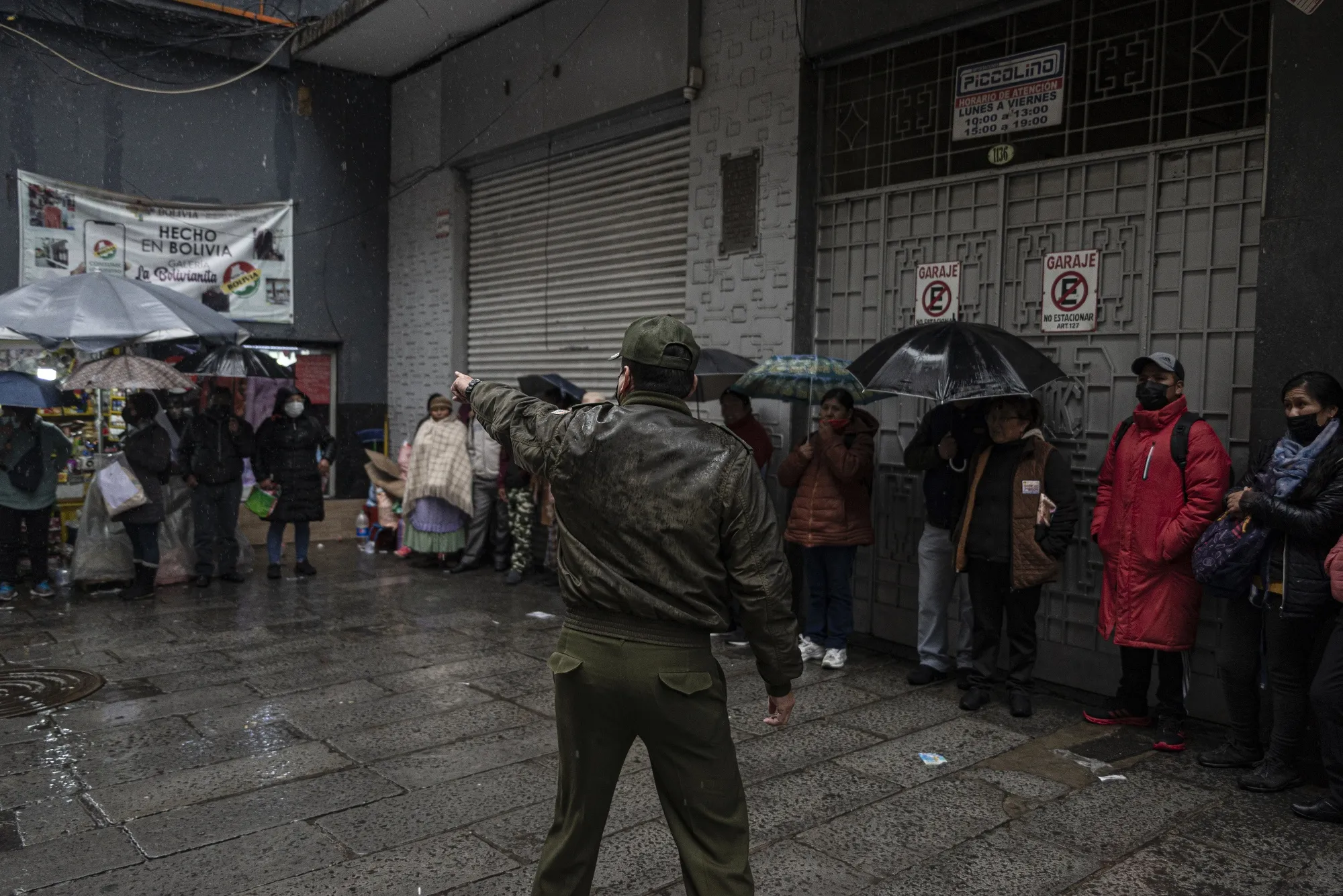 A police officer guides residents in line outside of the Bolivian Central Bank in La Paz, Bolivia, on&nbsp;March 29.
