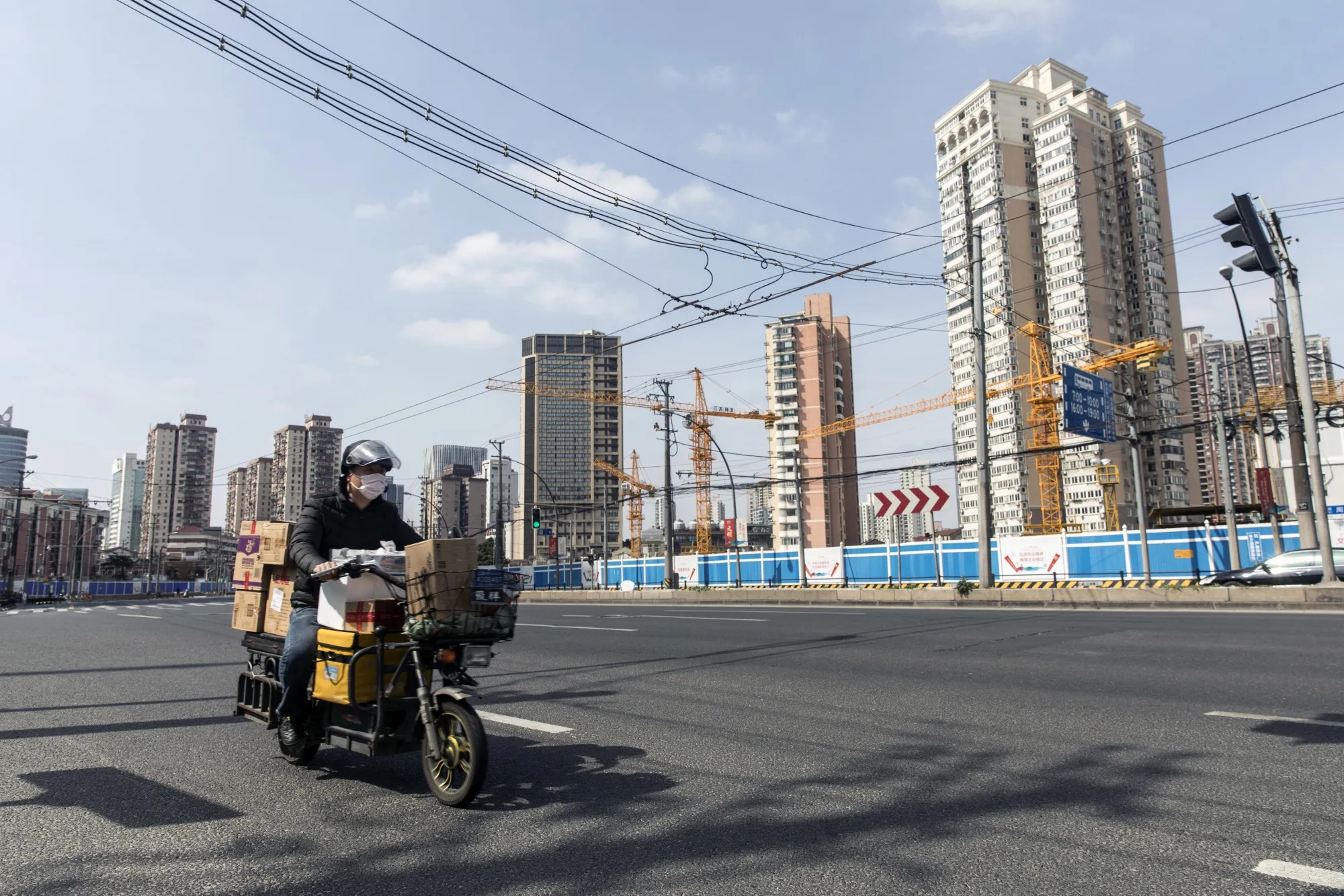 A delivery driver wearing a protective mask travels along a road past an idle construction site in Shanghai, China&nbsp;on&nbsp;Feb. 27.
