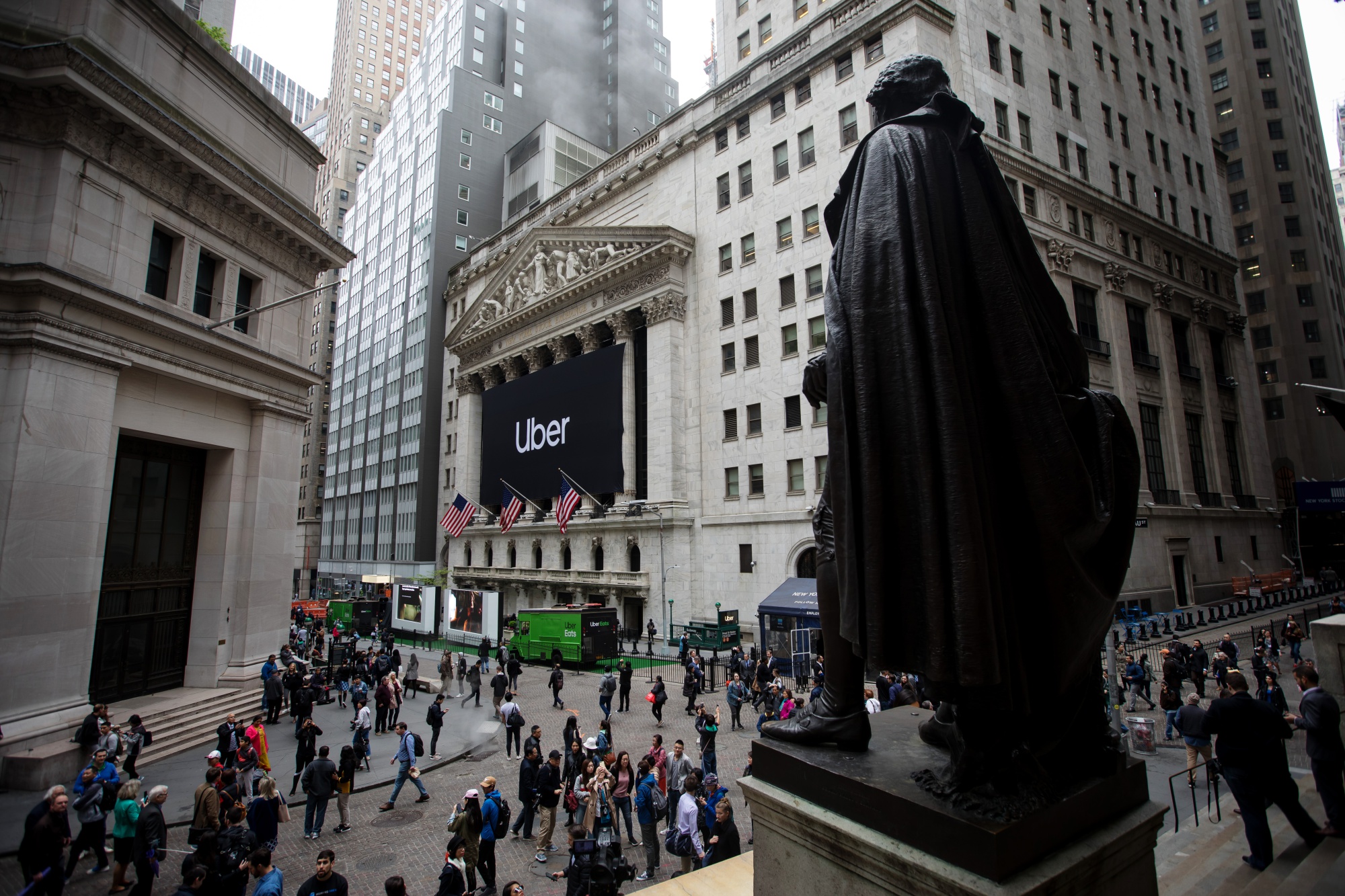 Pedestrians pass in front of the New York Stock Exchange during Uber Inc.'s IPO in New York on May 10.