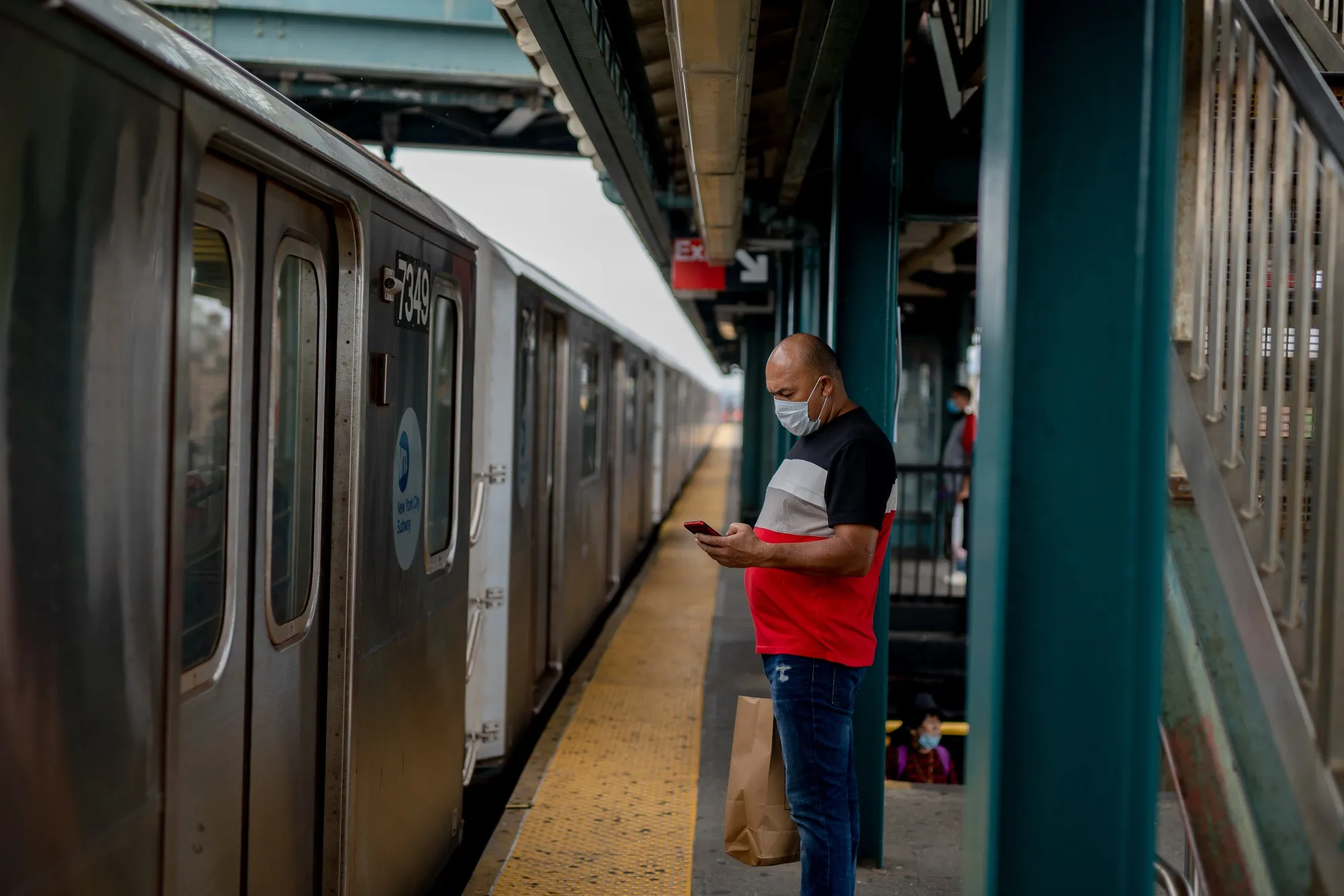 A commuter wears a protective mask while waiting on the subway platform in the Corona neighborhood of Queens on June 27.