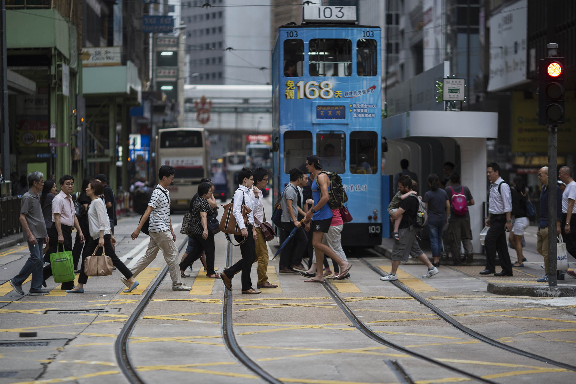 Pedestrians cross a road in front of a tram in the central business district of Hong Kong, China, on Thursday, July 9, 2015. After tumbling the most since the financial crisis on July 8 amid a record surge in volatility, the Hang Seng Index rebounded Thursday to its biggest gain in three months.
