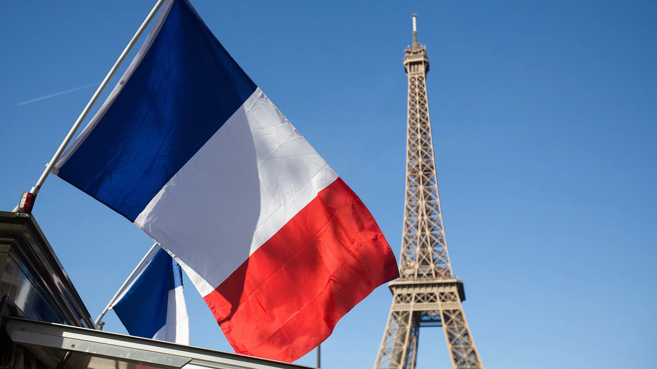 A French national flag flies near the Eiffel Tower in Paris, France on Sunday, Nov. 15, 2015. French investigators are still reconstructing how three teams of Islamic State militants killed at least 129 people in coordinated attacks in Paris on Friday.
