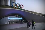 Visitors pose for photographs with the Olympic rings at the entrance to the Olympic Tower in Beijing, China.