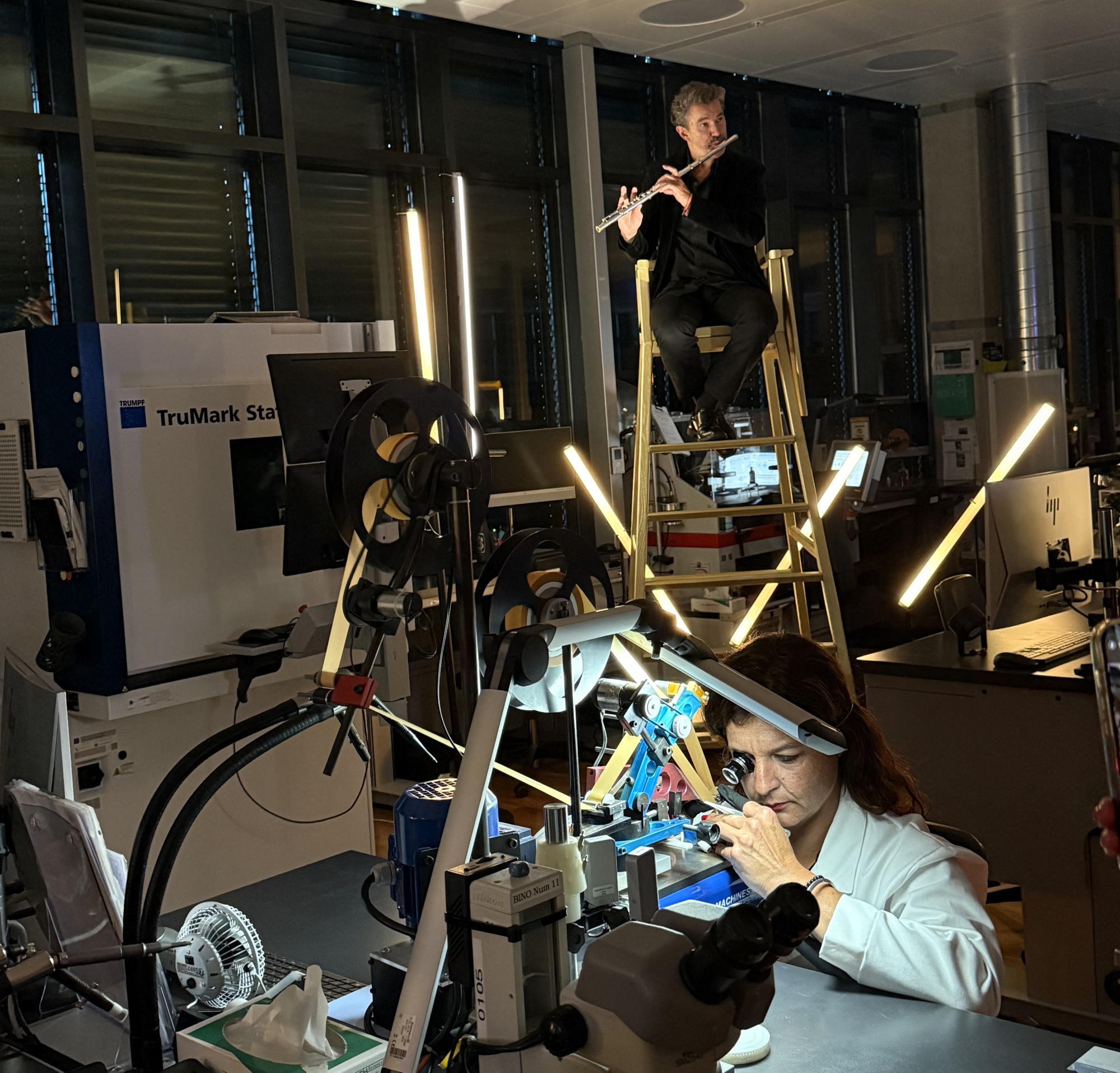 A floutist performs behind a watchmaker at the Vacheron Constantin manufacture in Plan-les-Ouates, Switzerland. Photographer: Chris Rovzar