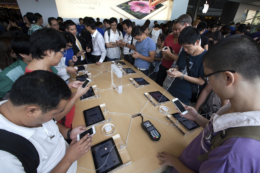 Customers examine Apple Inc. iPhone 5 smartphones at the company's store in Hong Kong, China. Photographer: Daniel J. Groshong/Bloomberg