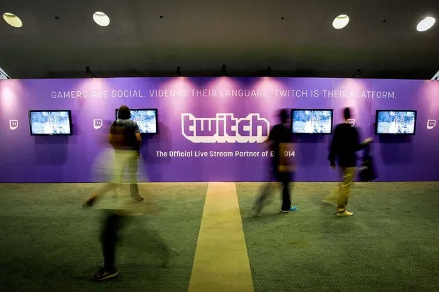 Attendees walk past televisions showing live streams of Twitch Interactive's video service during the E3 Electronic Entertainment Expo in Los Angeles on June 10