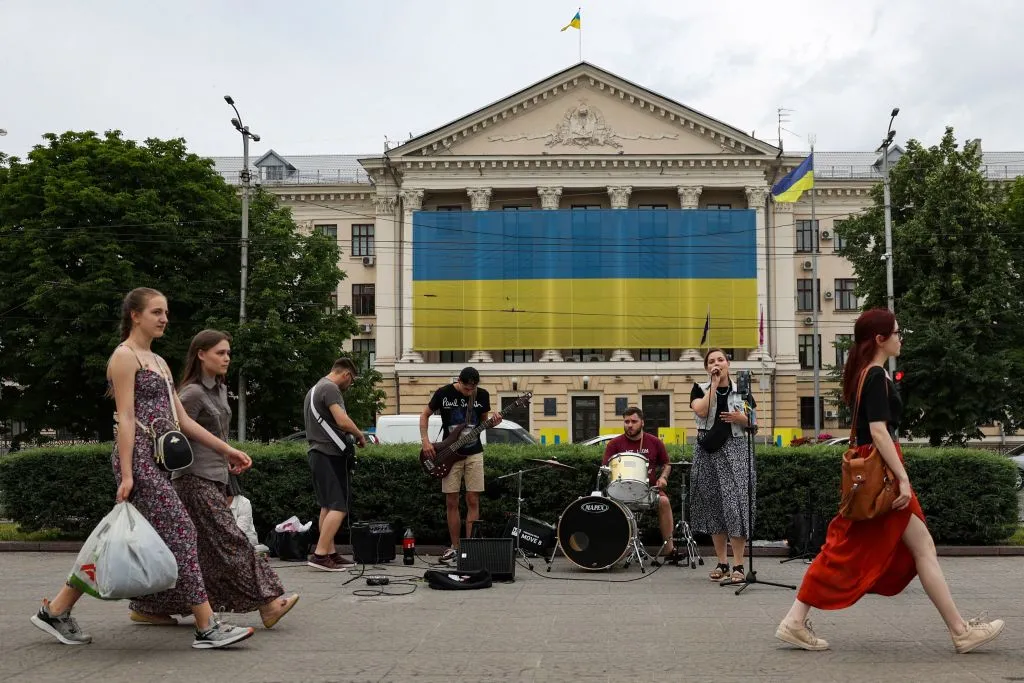 Pedestrians walk past a band playing music in Zaporizhzhia, on June 10.