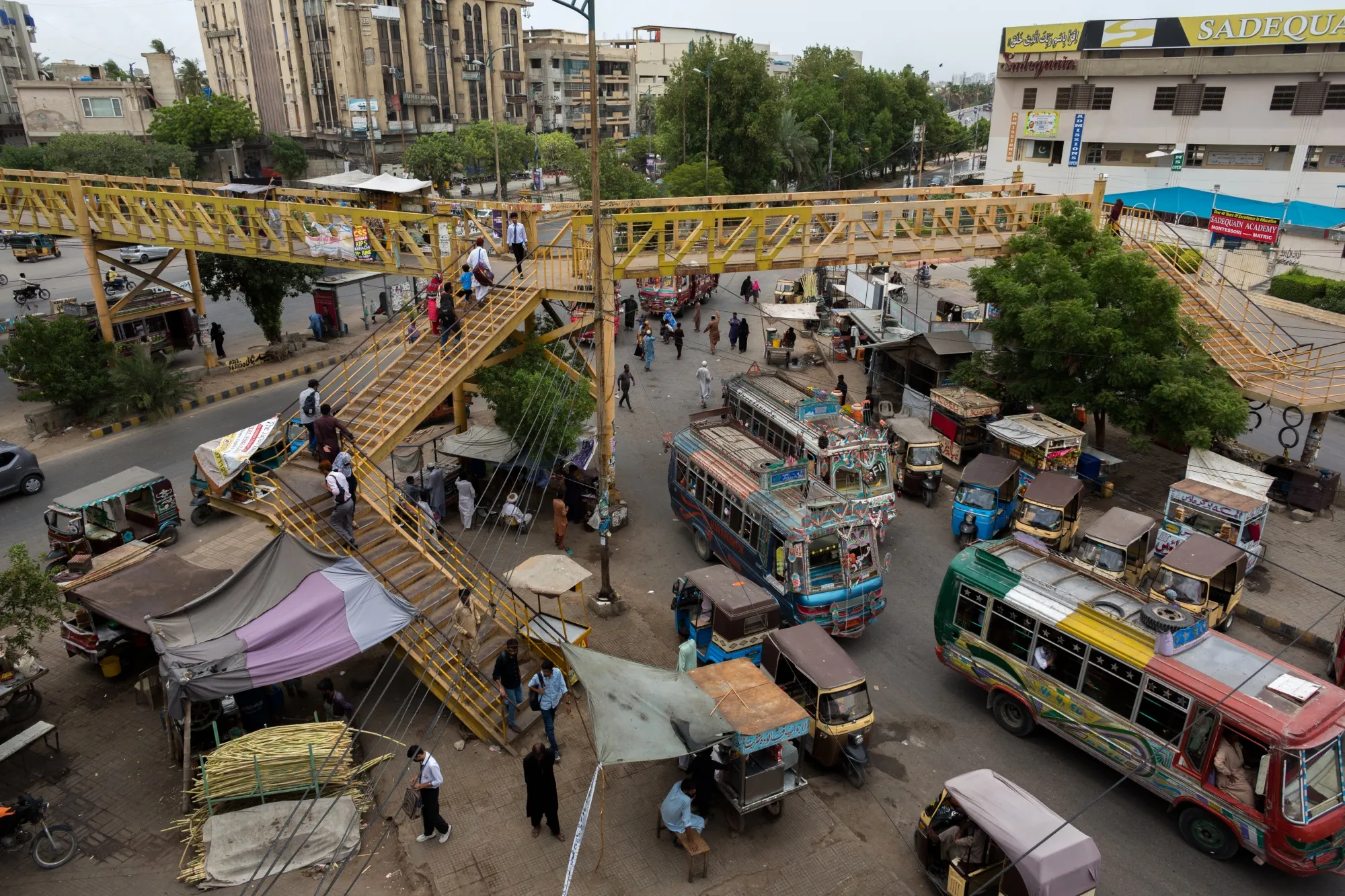 People cross over a pedestrian bridge under a traffic junction in Karachi.