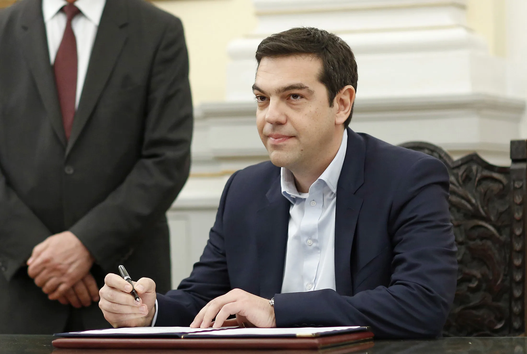 Alexis Tsipras, Greek Prime Minister-elect, signs a book as he is sworn in as prime minister at a ceremony at the presidential palace in Athens, Greece, Jan. 26, 2015.

