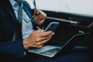 Businessman Working On Smartphone and Laptop In Car