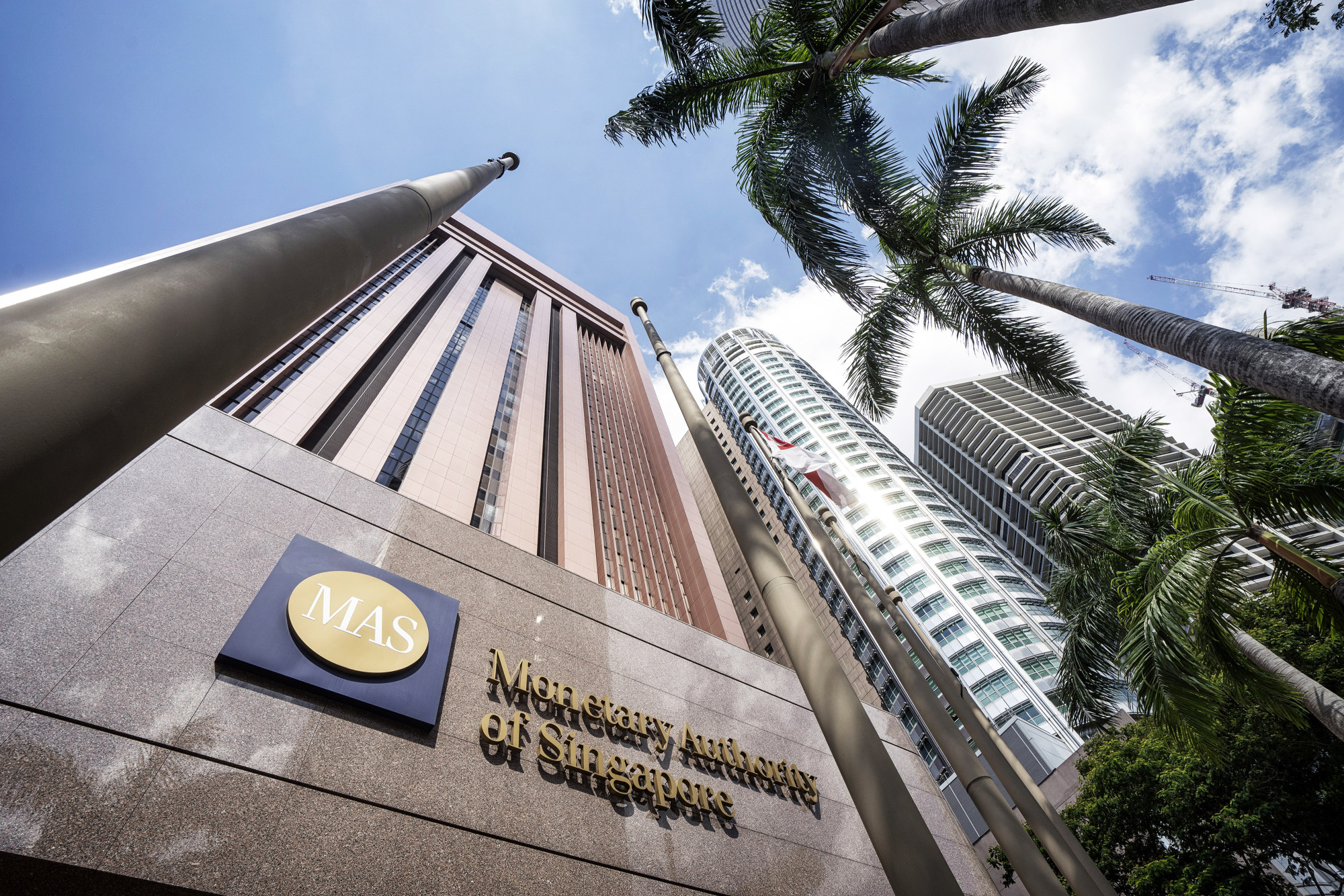 The Singapore national flag flies next to signage for the Monetary Authority of Singapore (MAS) displayed outside the central bank's headquarters in Singapore.
