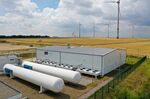 Wind turbines stand in view of a hydrogen electrolysis plant in Mainz, Germany.